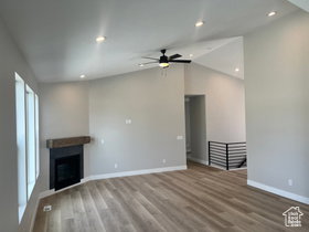 Spacious room featuring vaulted ceilings, recessed lighting, and wood-finish flooring