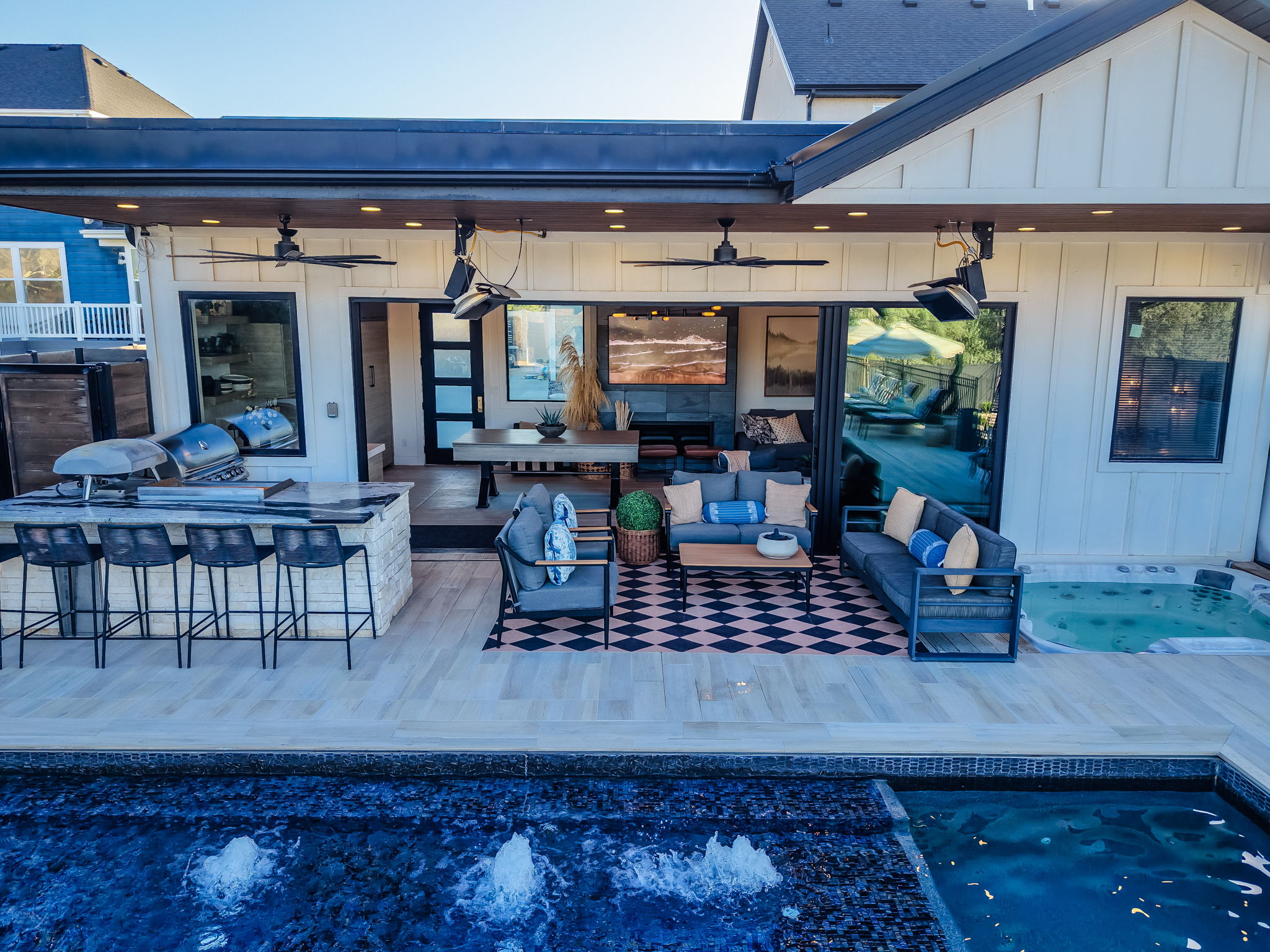Expansive outdoor living area featuring a covered patio with recessed lighting and ceiling fans