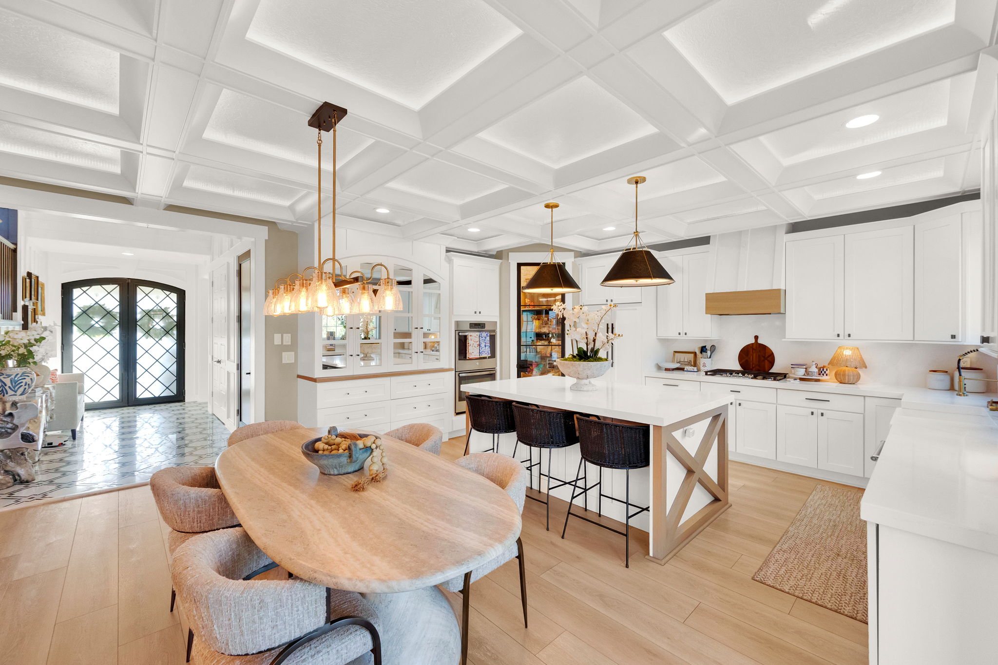 Gourmet kitchen featuring a substantial island with seating, integrated appliances, white cabinetry, and wood-finish flooring