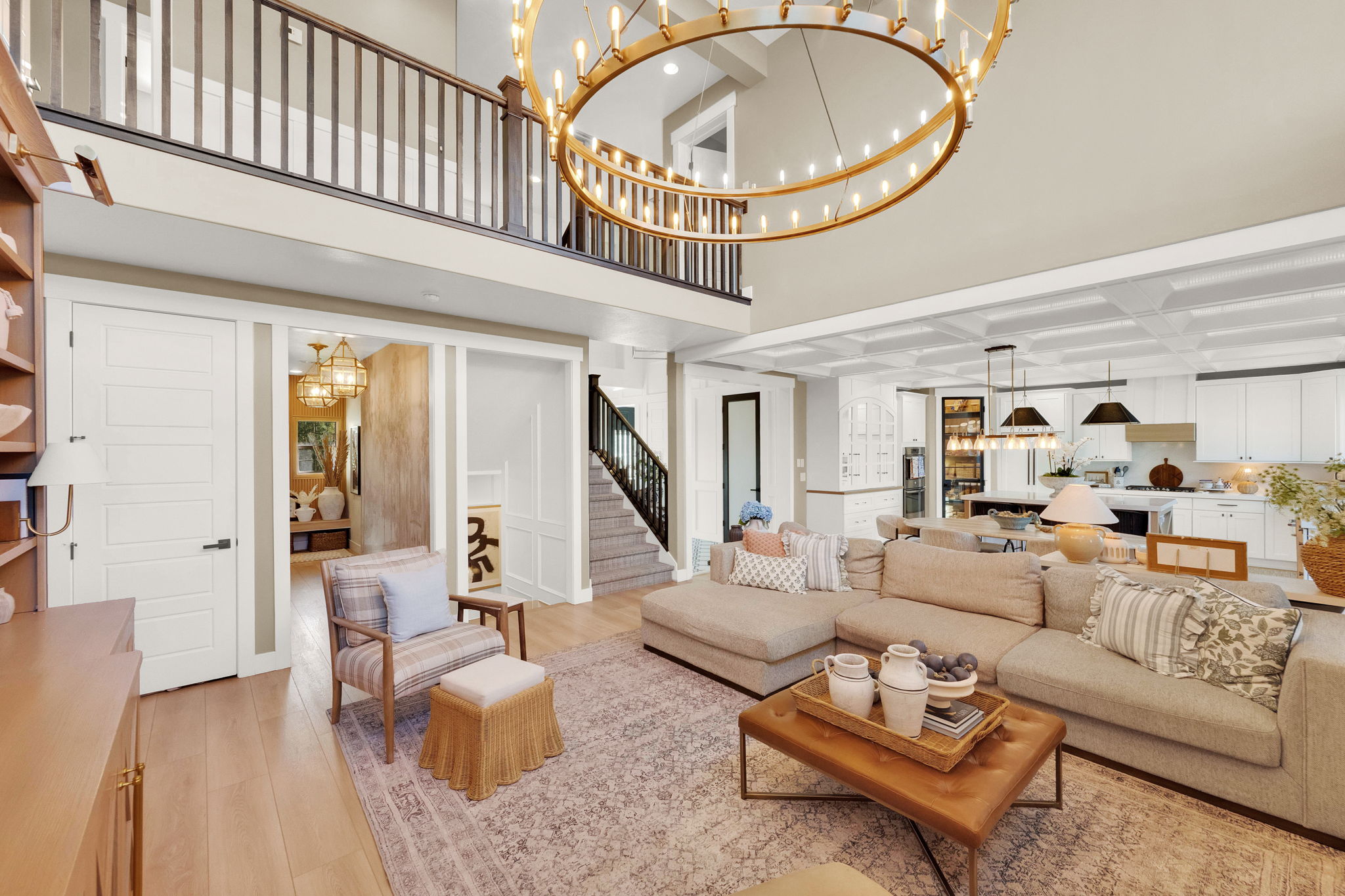 Great room featuring high ceilings, a grand circular chandelier, wood-finish flooring, a coffered ceiling, and an open-concept kitchen