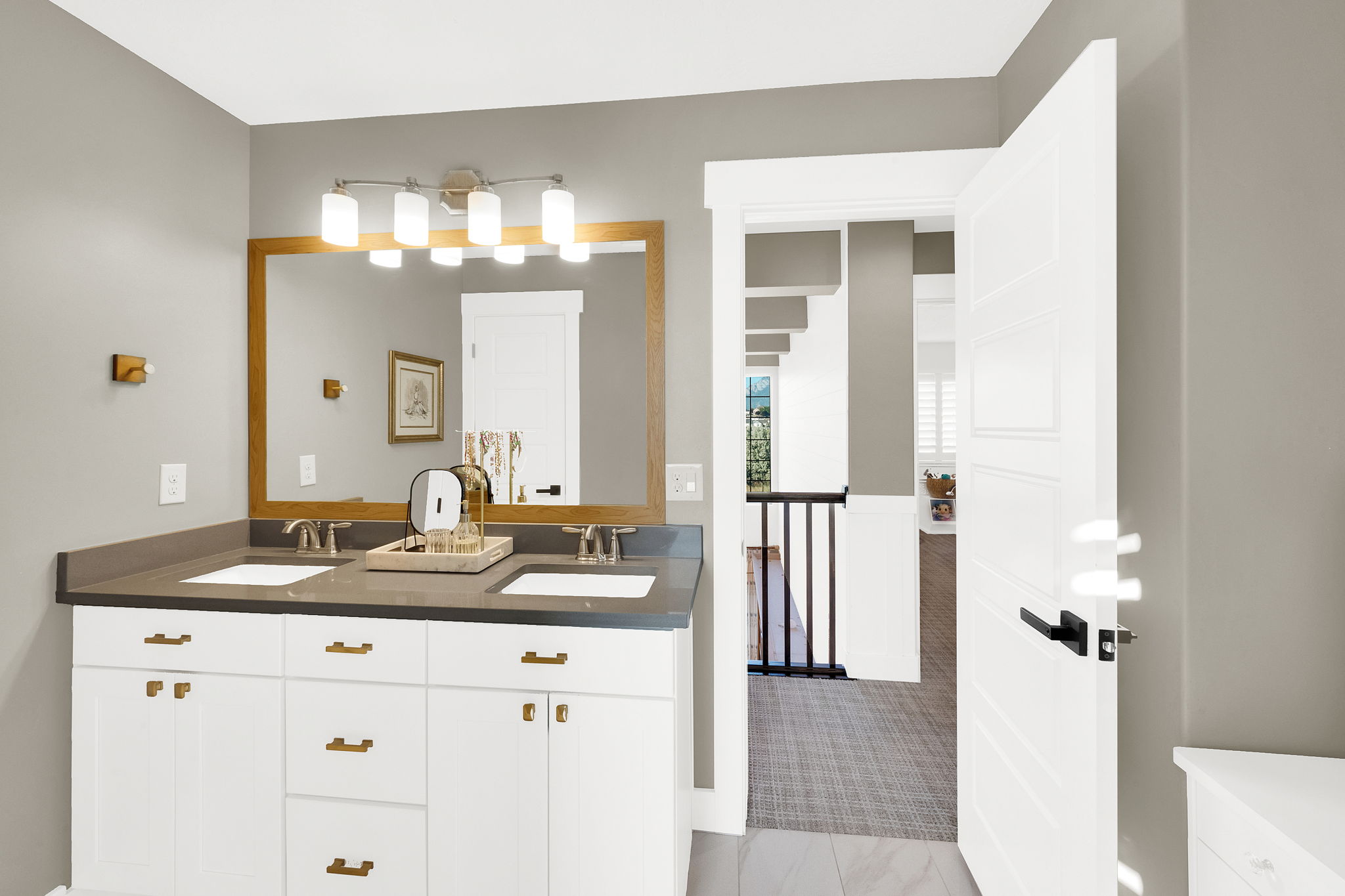 Bathroom vanity featuring dual undermount sinks, bronze faucets, and a dark stone-finish countertop