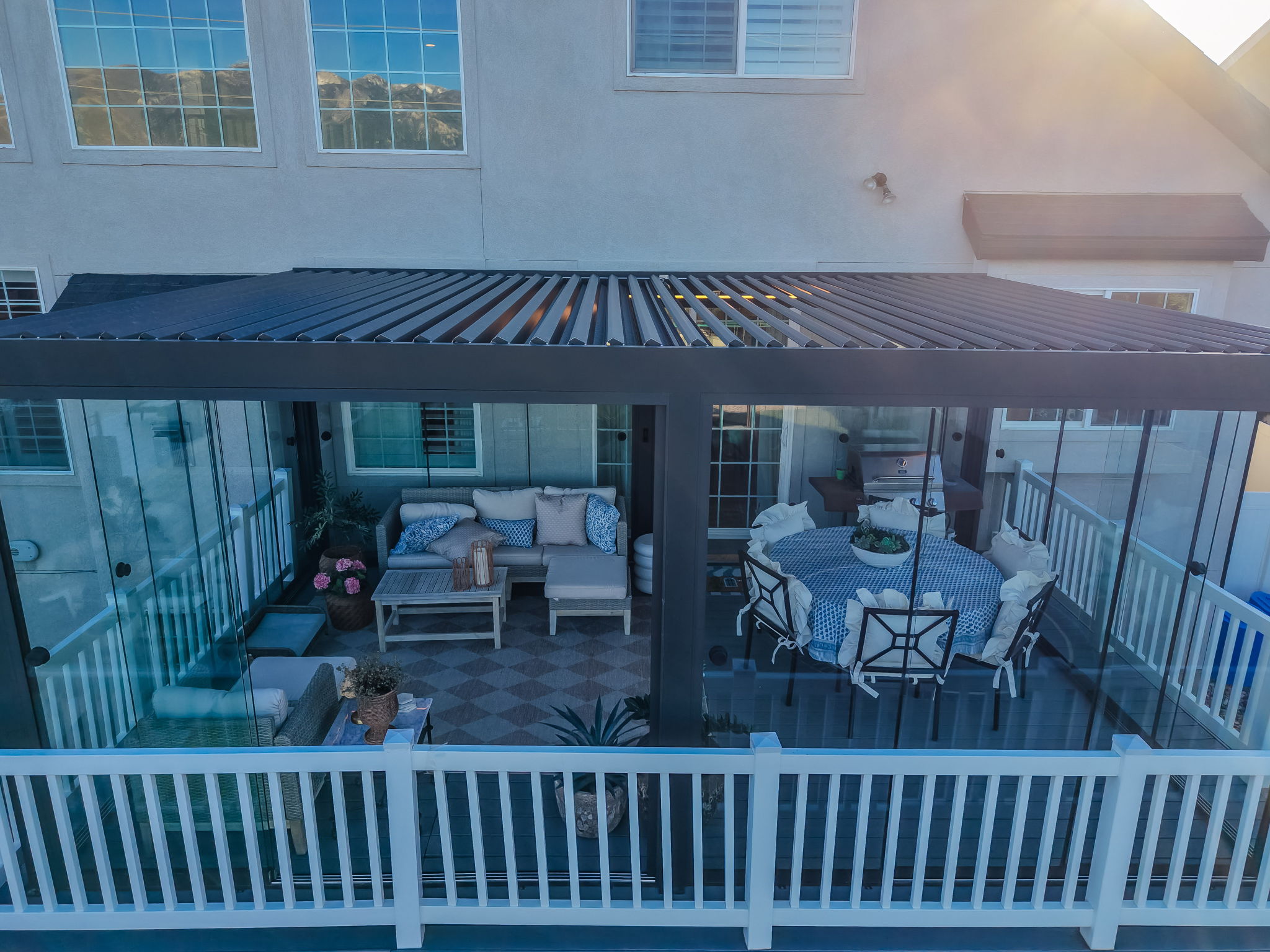 Covered outdoor living space featuring a louvered pergola roof and glass panel enclosures