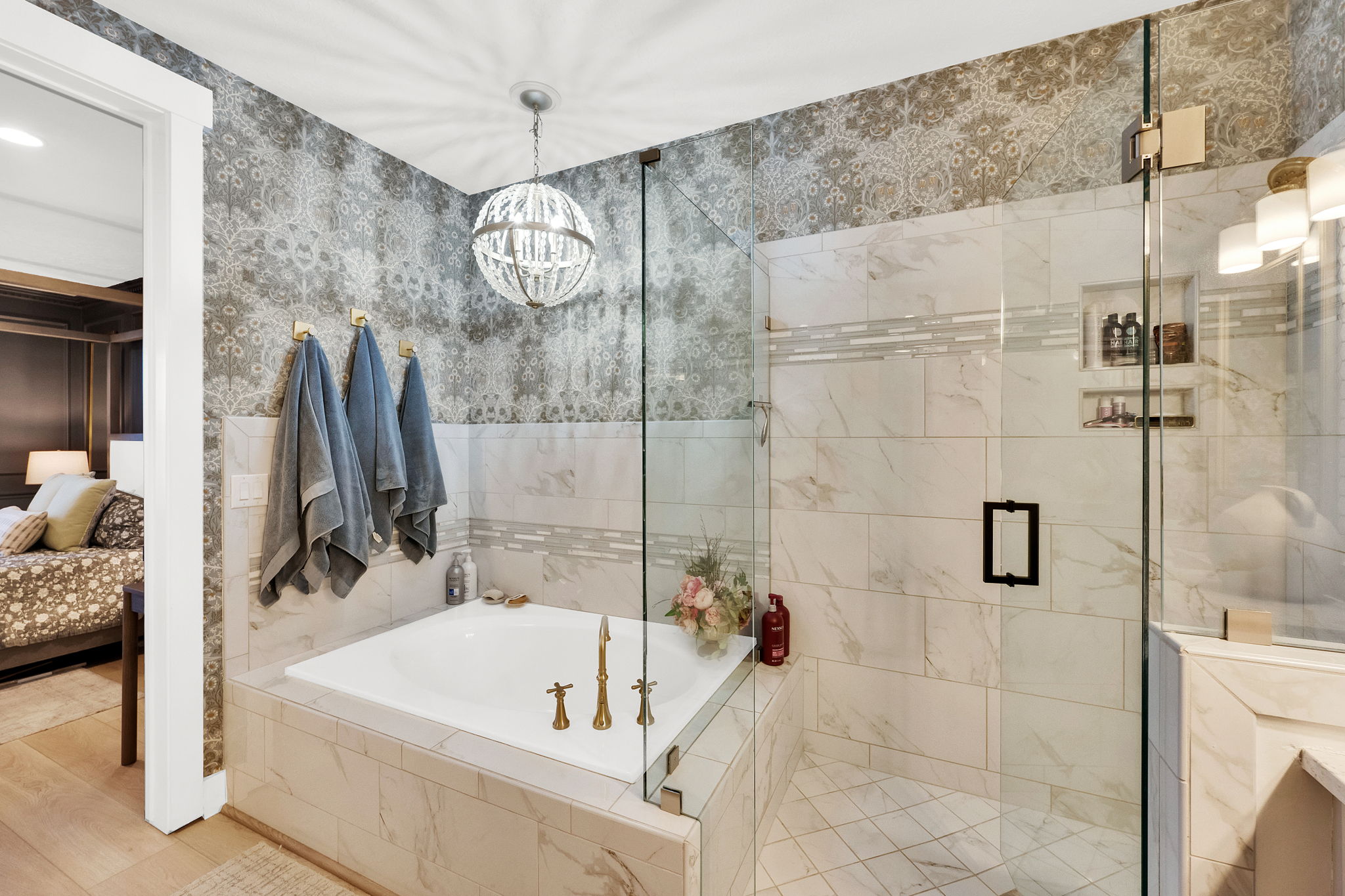Spa-inspired bathroom featuring a built-in tub with brass fixtures, a glass-enclosed shower with a tiled bench and recessed shelving, and decorative wall tiling