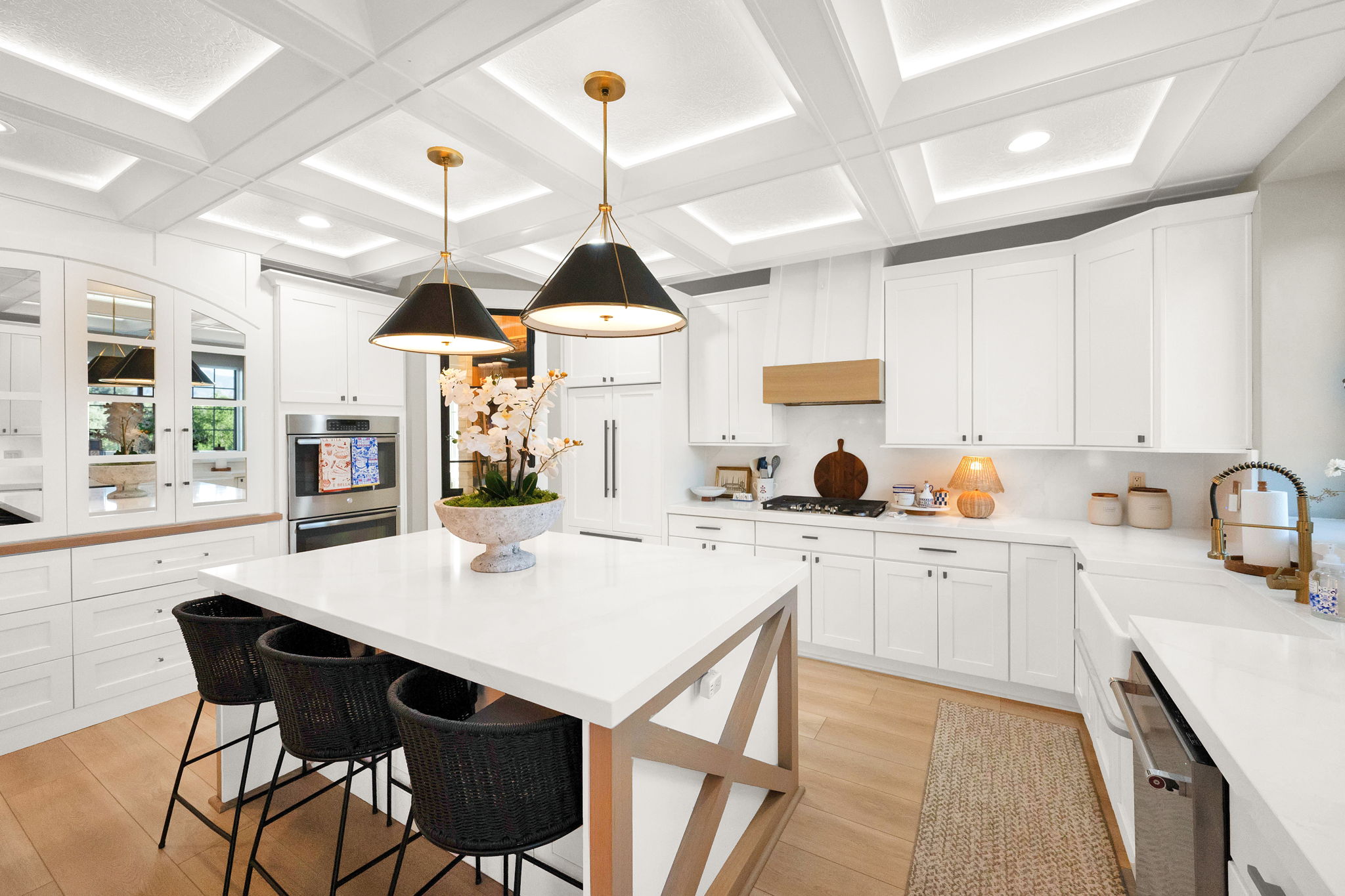 Modern kitchen featuring a large central island with seating, white shaker cabinetry, and wood-finish flooring