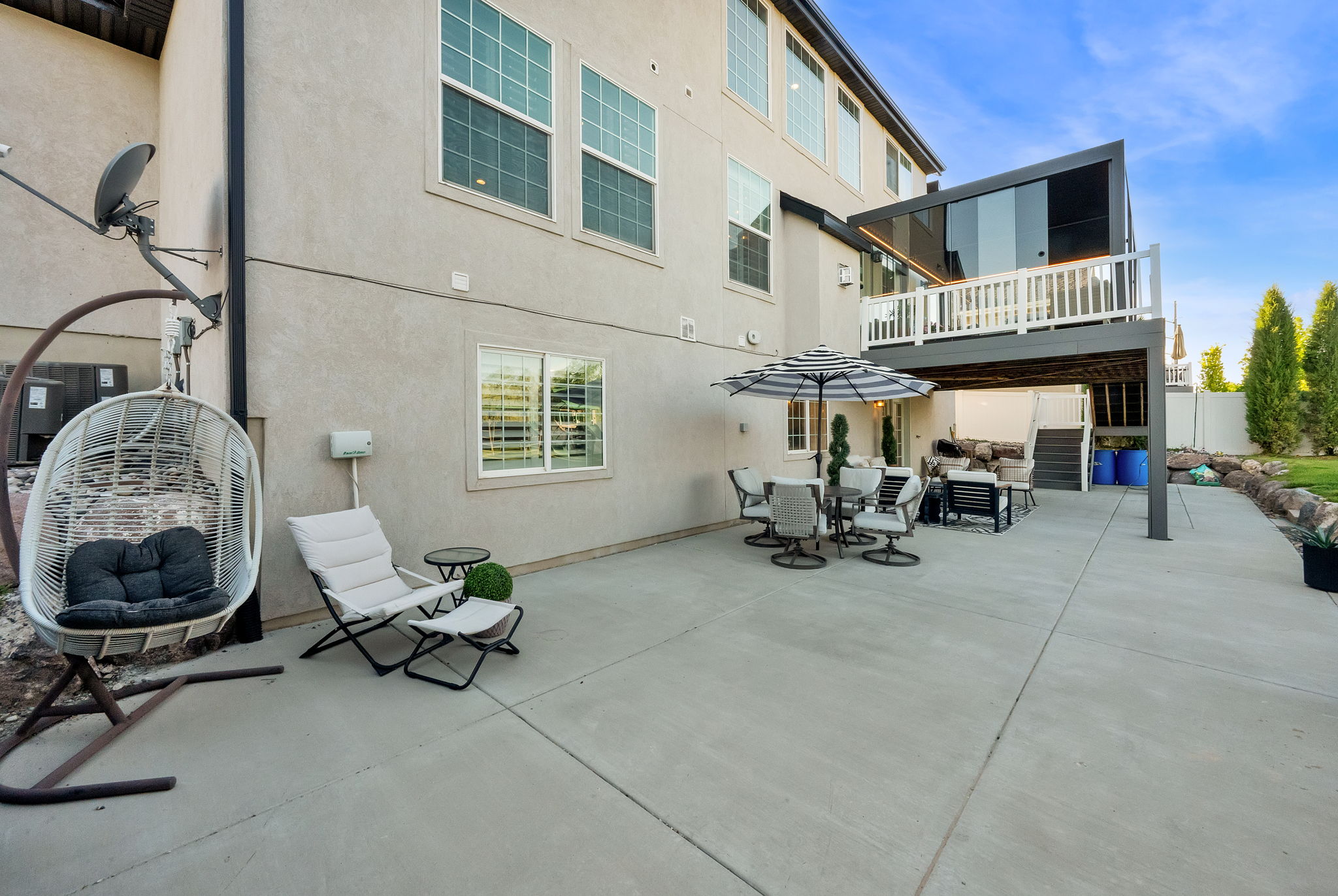 Expansive concrete patio with a full-width upper deck featuring a glass enclosure