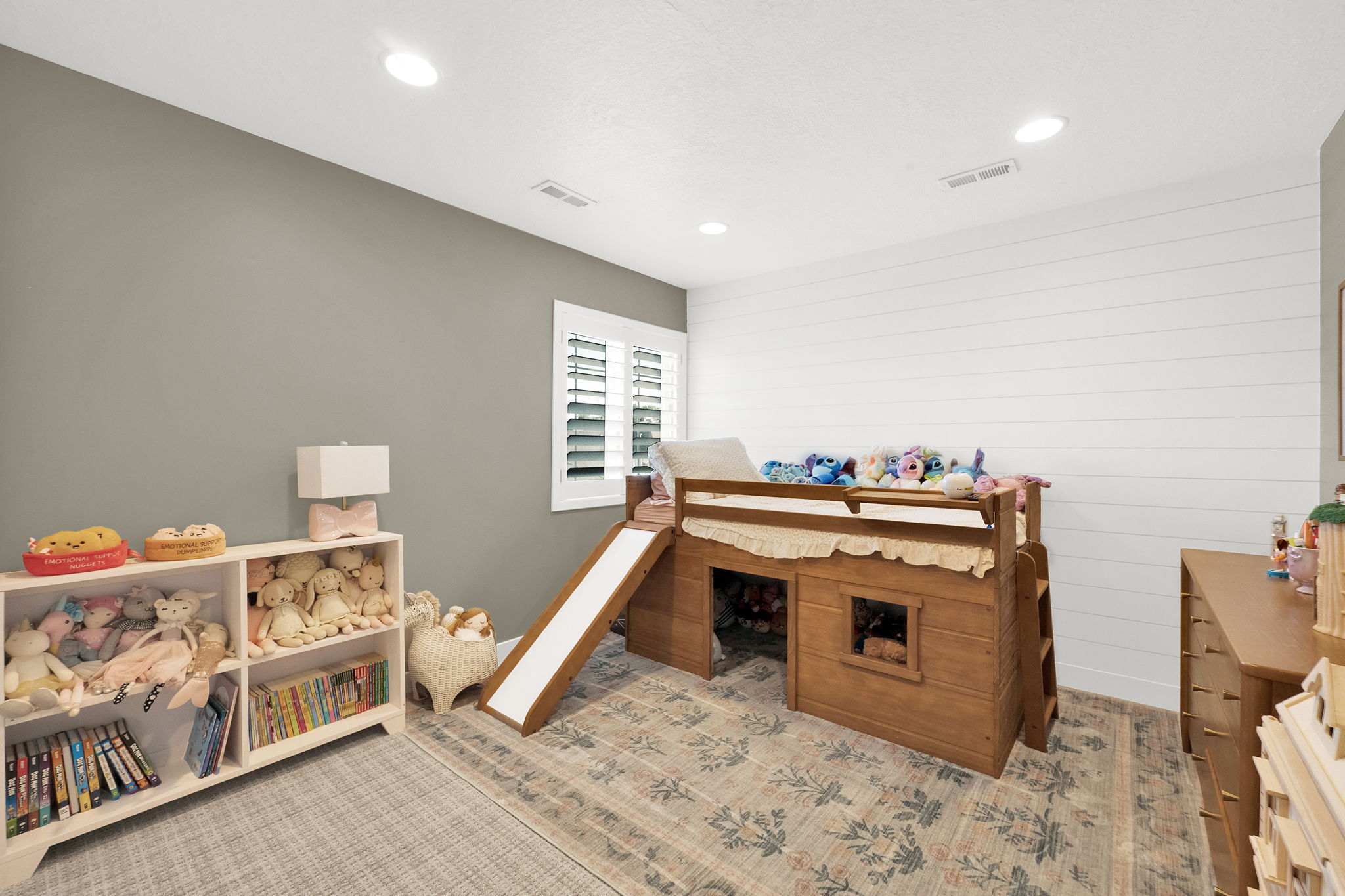 Bedroom featuring recessed lighting, a window with white plantation shutters, and a shiplap accent wall