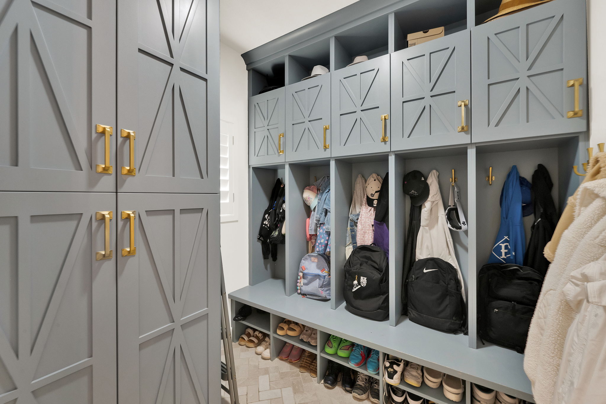 Custom built-in mudroom cabinetry with a light blue finish and gold-tone hardware