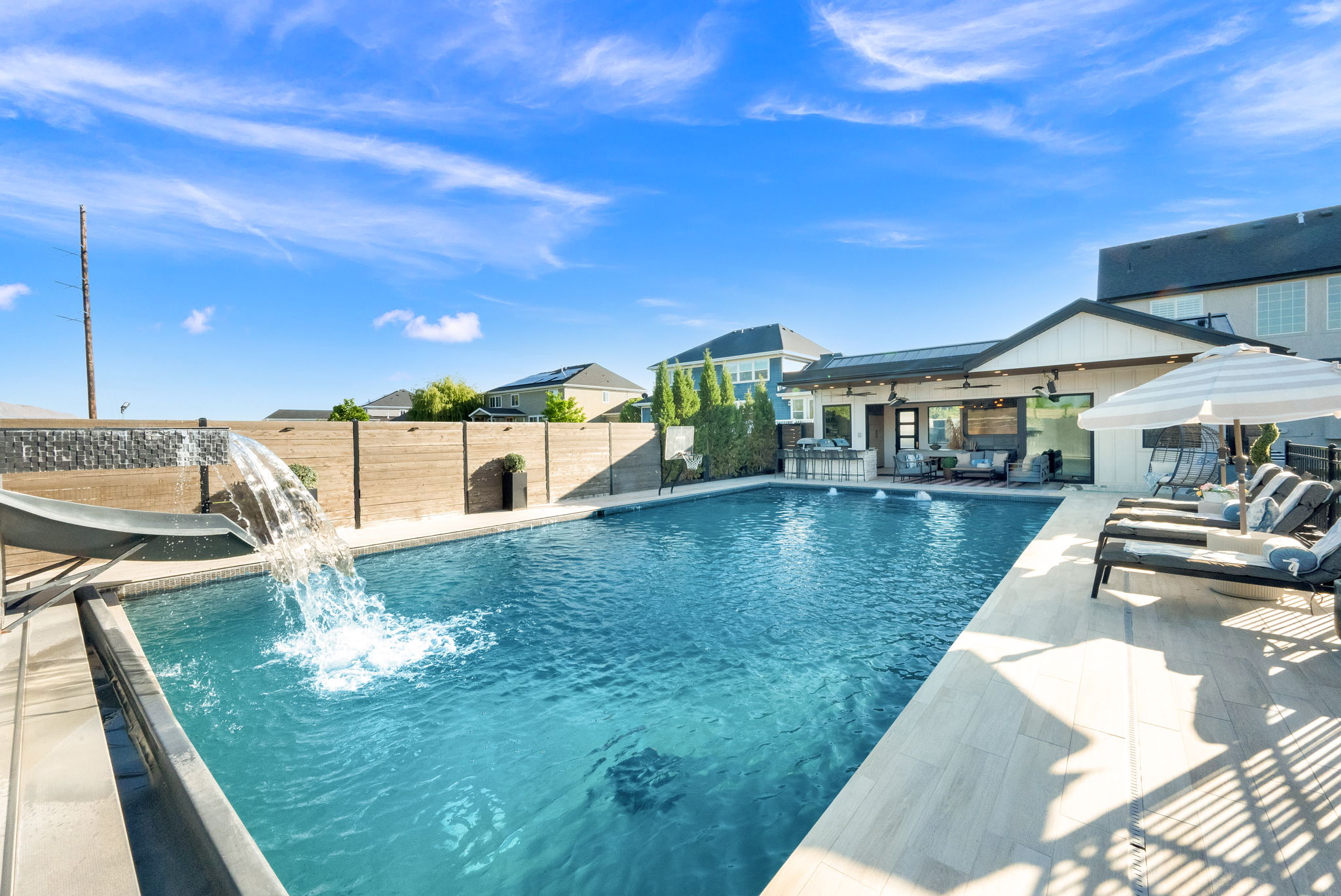 Expansive swimming pool featuring a waterfall and integrated slide