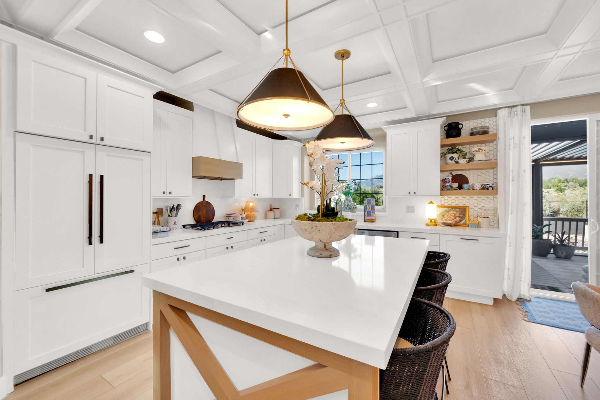 Spacious kitchen featuring white cabinetry, a large center island with seating, pendant lighting, built-in appliances, and light wood-finish flooring