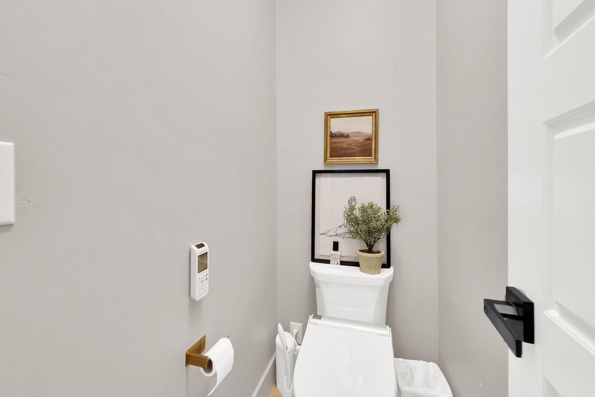 Compact water closet featuring light gray walls and a white toilet