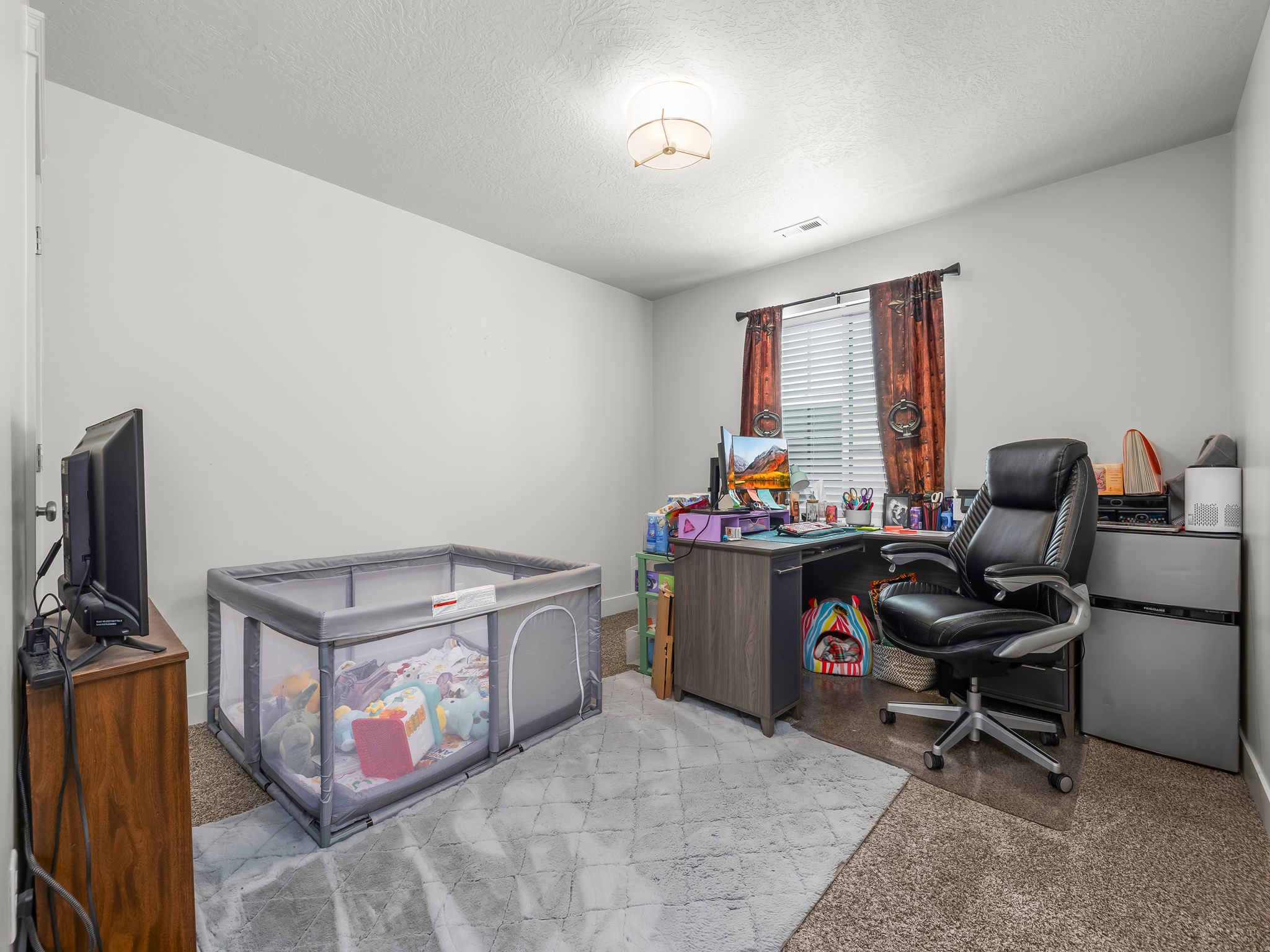 Bright room featuring a window with horizontal blinds, a neutral wall color, and a flush-mount ceiling light fixture