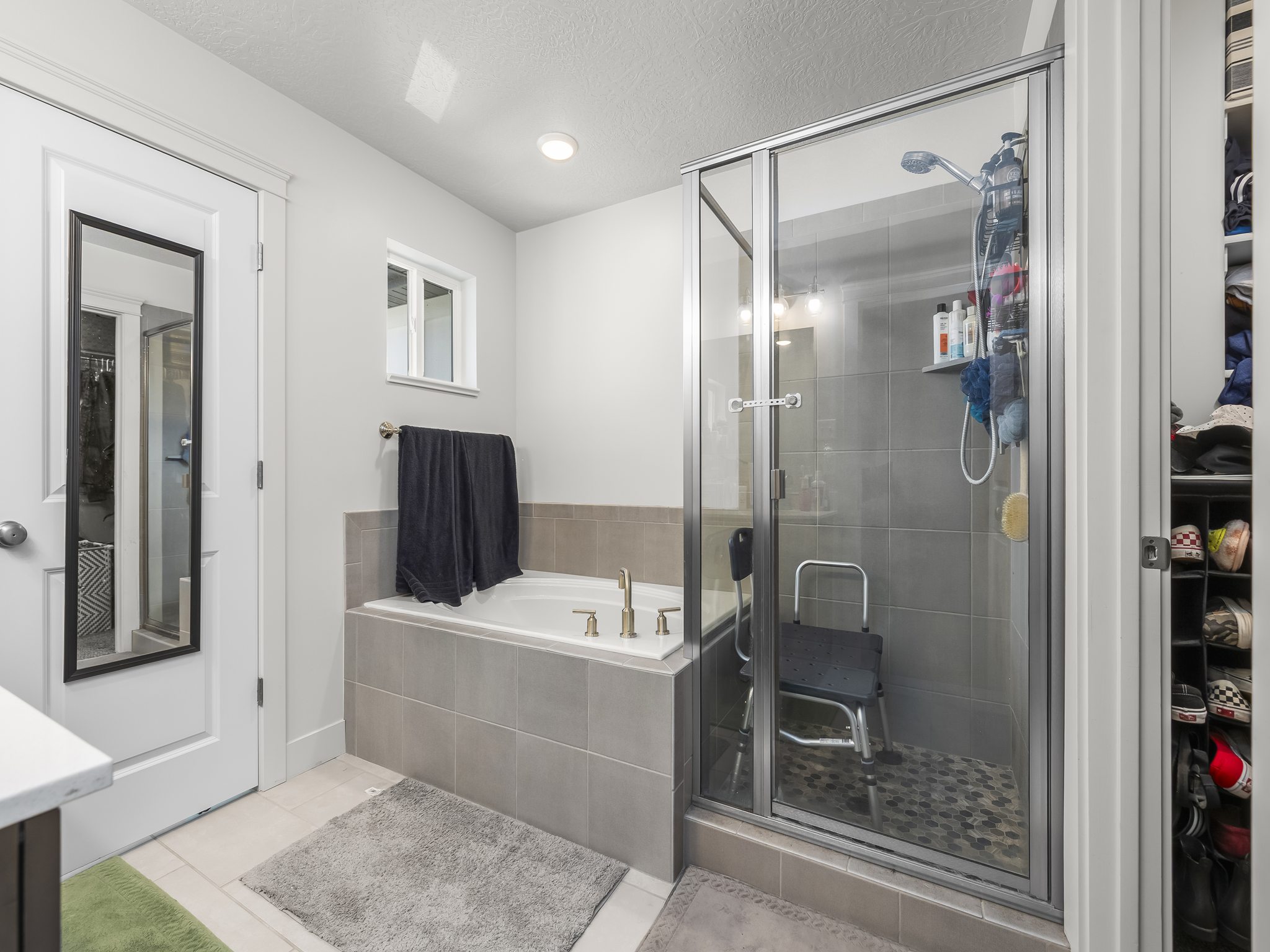 Bathroom featuring an enclosed shower with glass doors, a built-in tub with tile surround, and an integrated storage nook