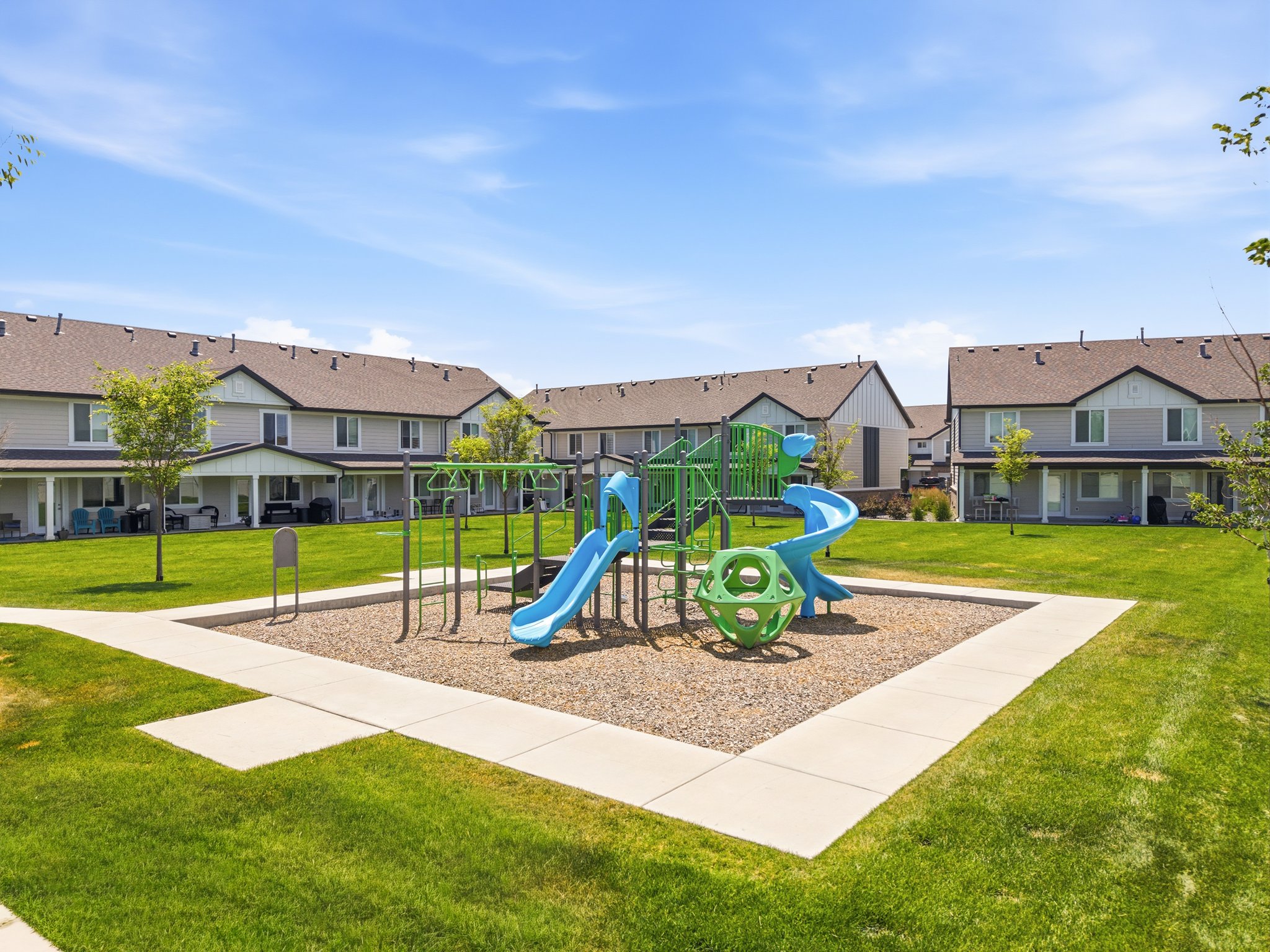 Central playground featuring multiple slides and climbing structures, surrounded by a manicured lawn