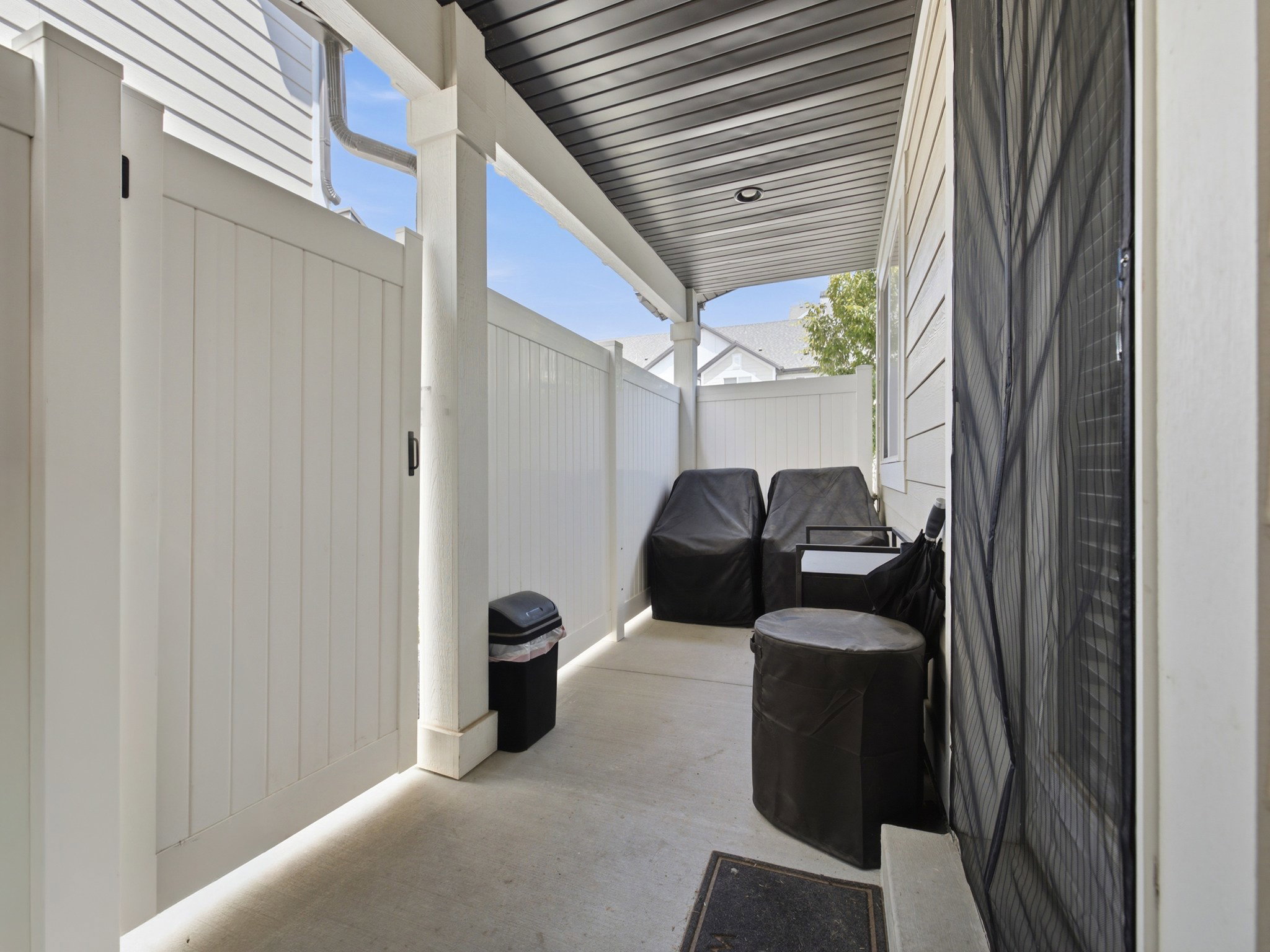 Covered patio featuring a concrete slab and white vinyl fencing