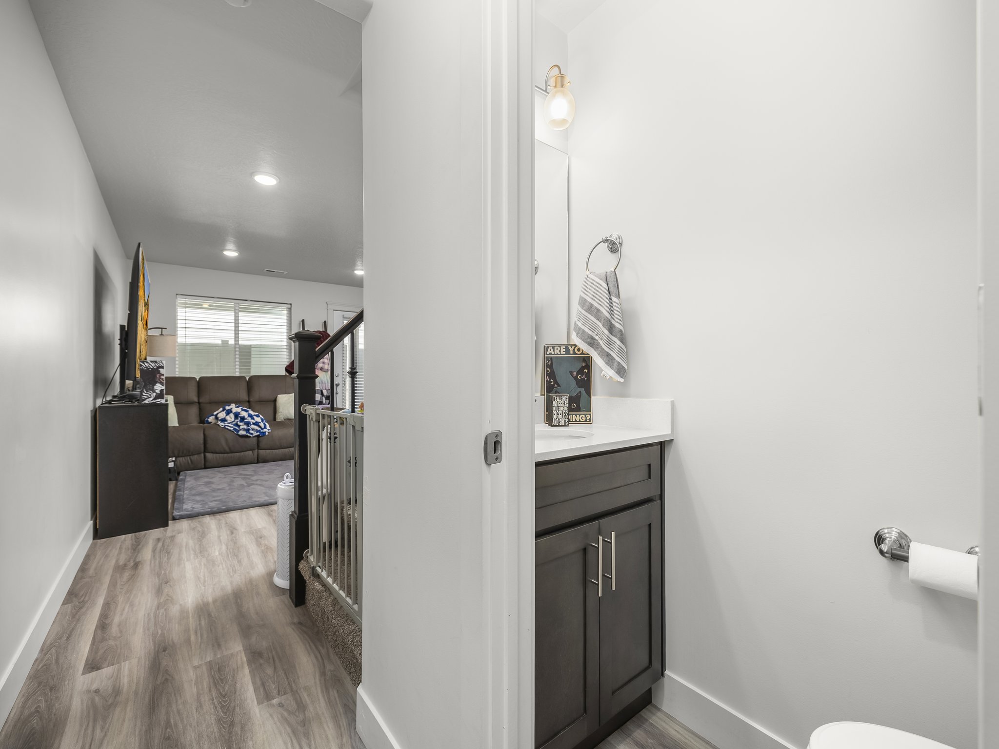 Powder room featuring a dark wood vanity with a white countertop, chrome hardware, and a single wall-mounted light fixture