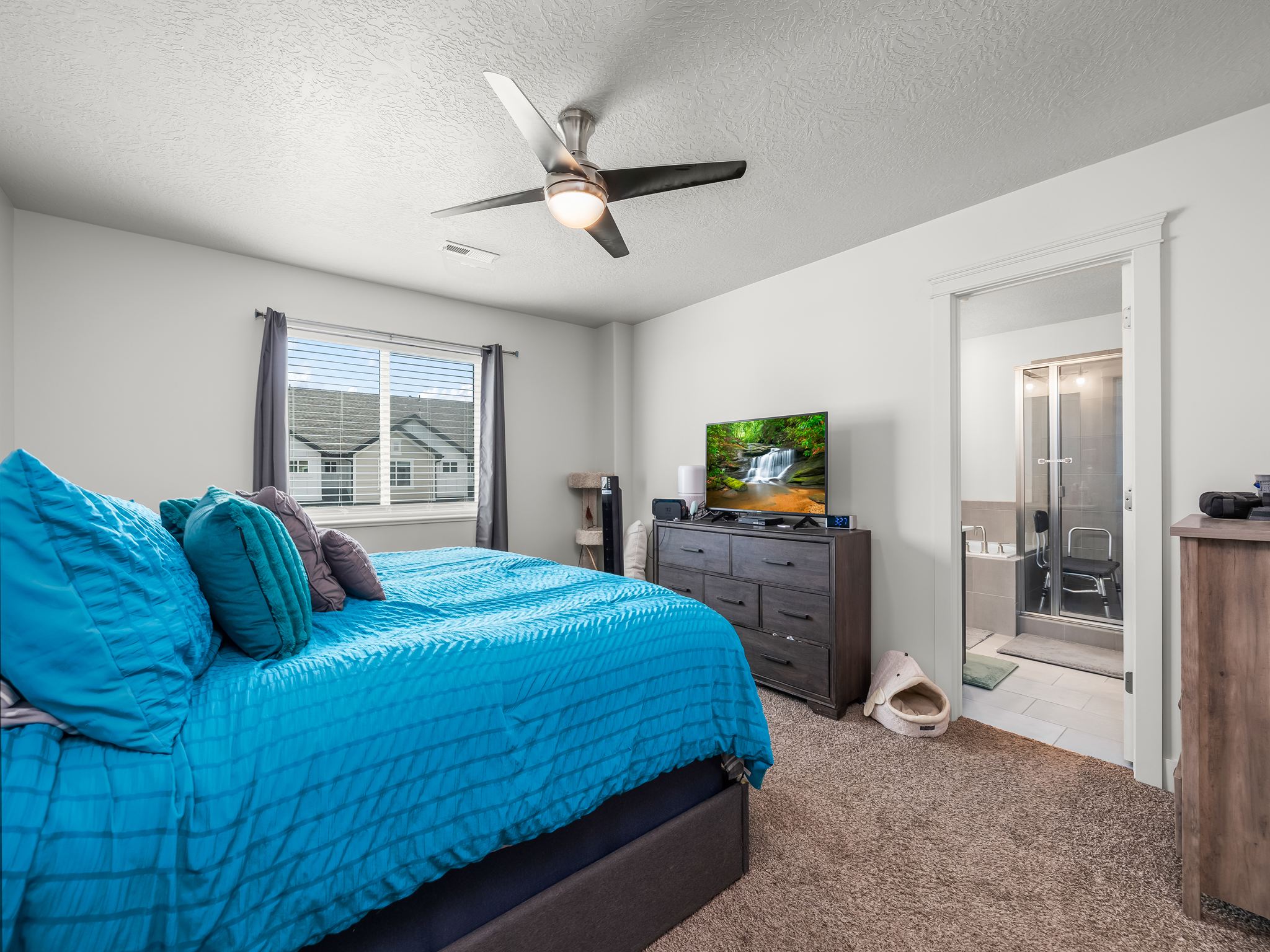 Carpeted bedroom with a ceiling fan light fixture and a window featuring horizontal blinds