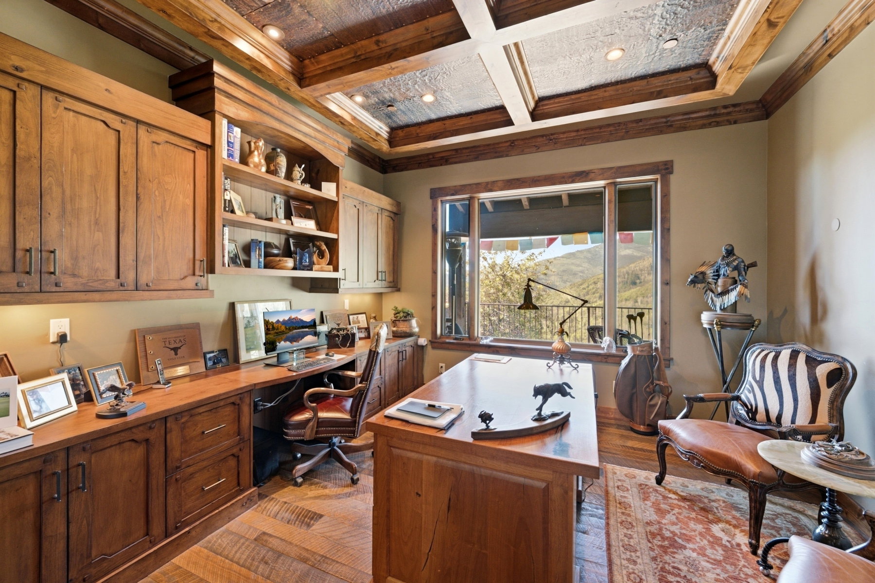 Spacious room featuring extensive built-in wood cabinetry and shelving, a coffered ceiling with recessed lighting, large windows with wood trim, and wide plank wood-finish flooring