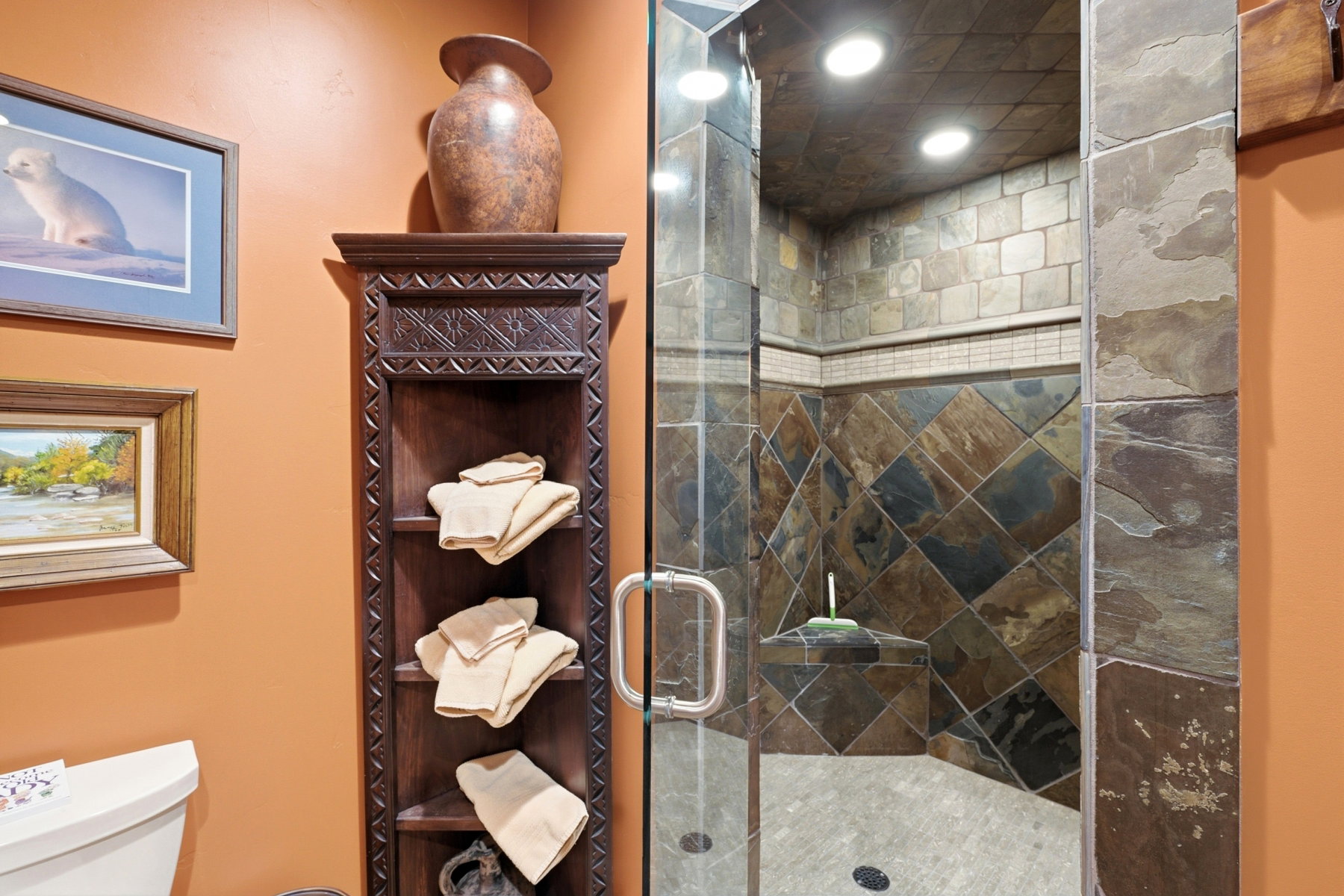 Walk-in shower featuring a glass enclosure, natural stone tile, recessed lighting, and a built-in shower bench