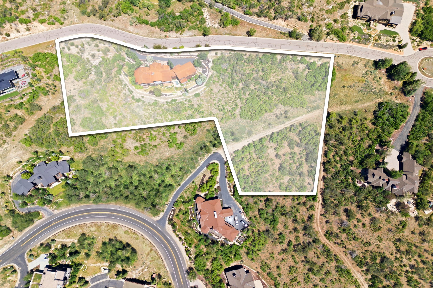 Expansive undeveloped land parcel featuring significant acreage, varied topography, and surrounding residential structures