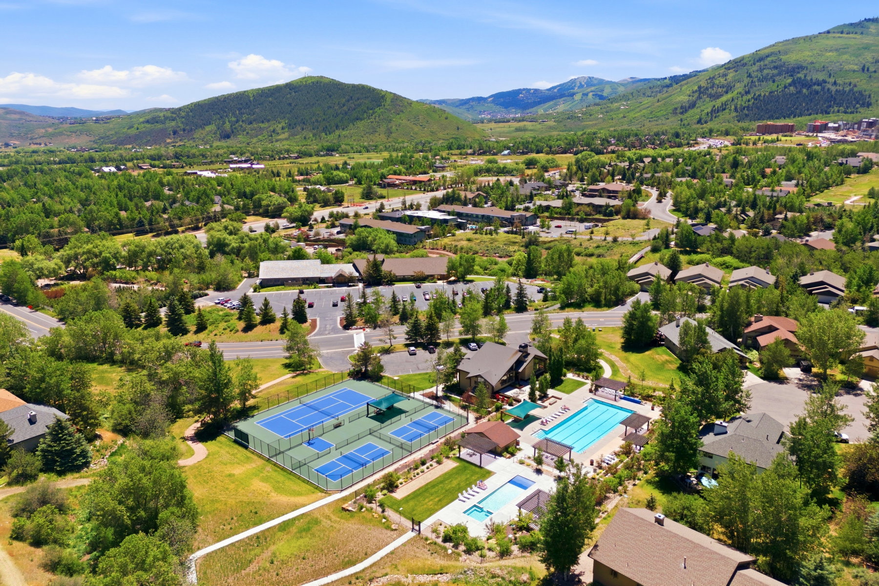 Community recreational facilities featuring multiple tennis and pickleball courts, a large swimming pool, and a smaller spa pool