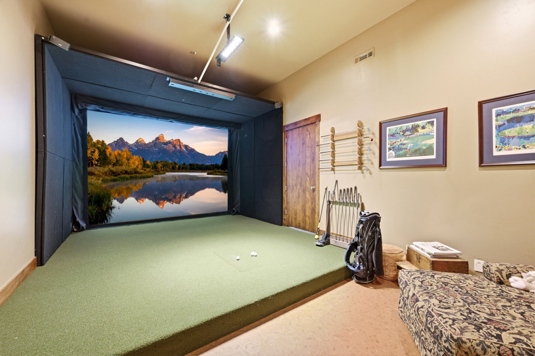 Dedicated indoor golf simulator with an expansive screen and a golf turf playing surface