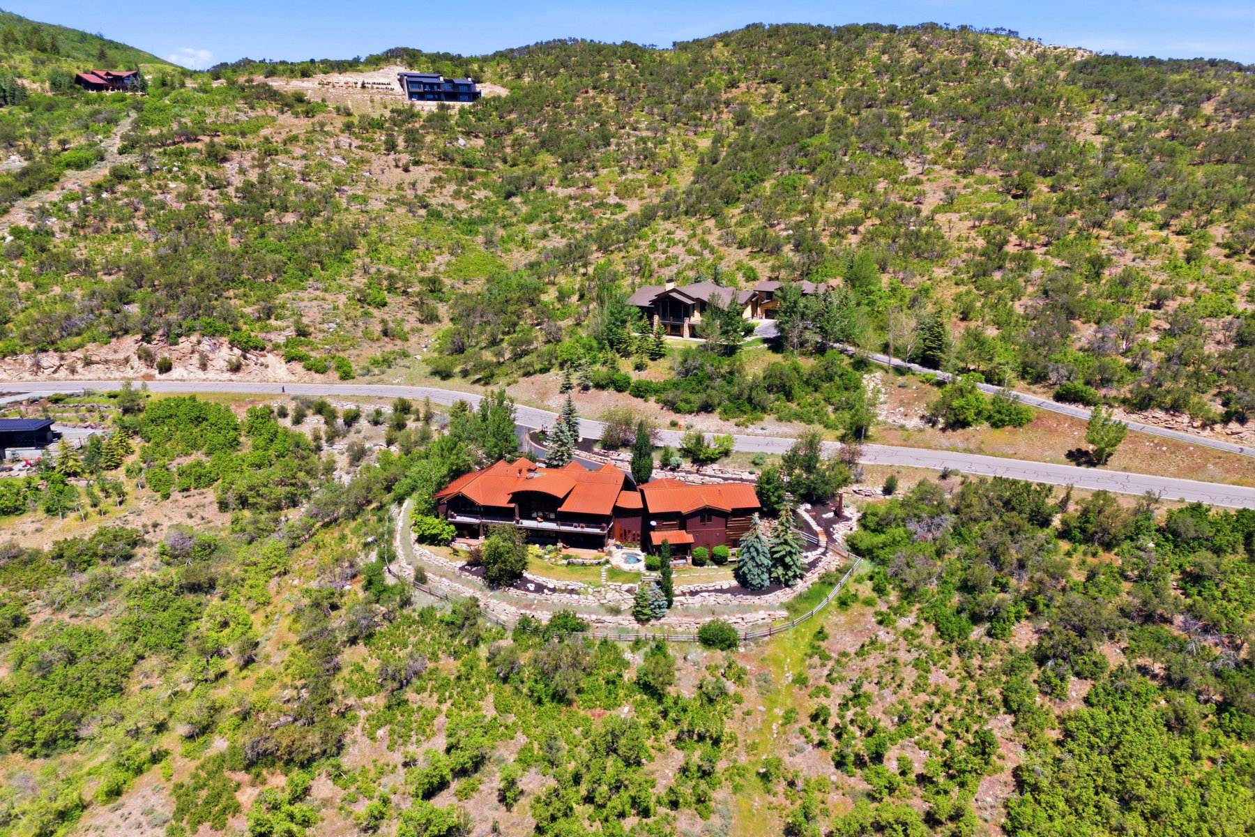 Hillside property featuring a multi-level structure with a red tile roof and multiple gables
