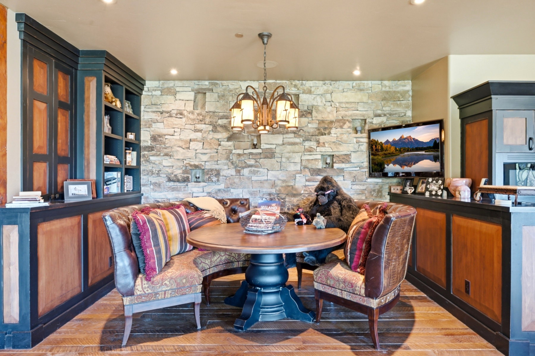 Dining area featuring a stone accent wall, wood-finish flooring, and a wrought iron chandelier