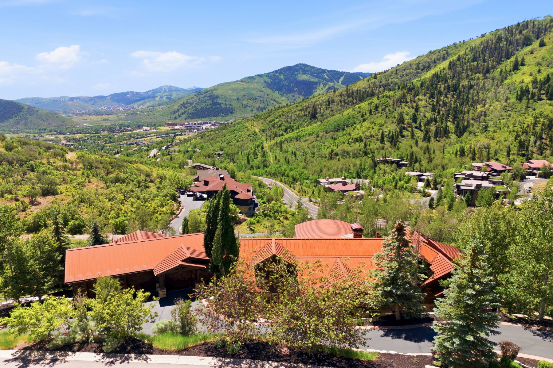 Expansive mountain landscape featuring verdant hillsides and distant structures