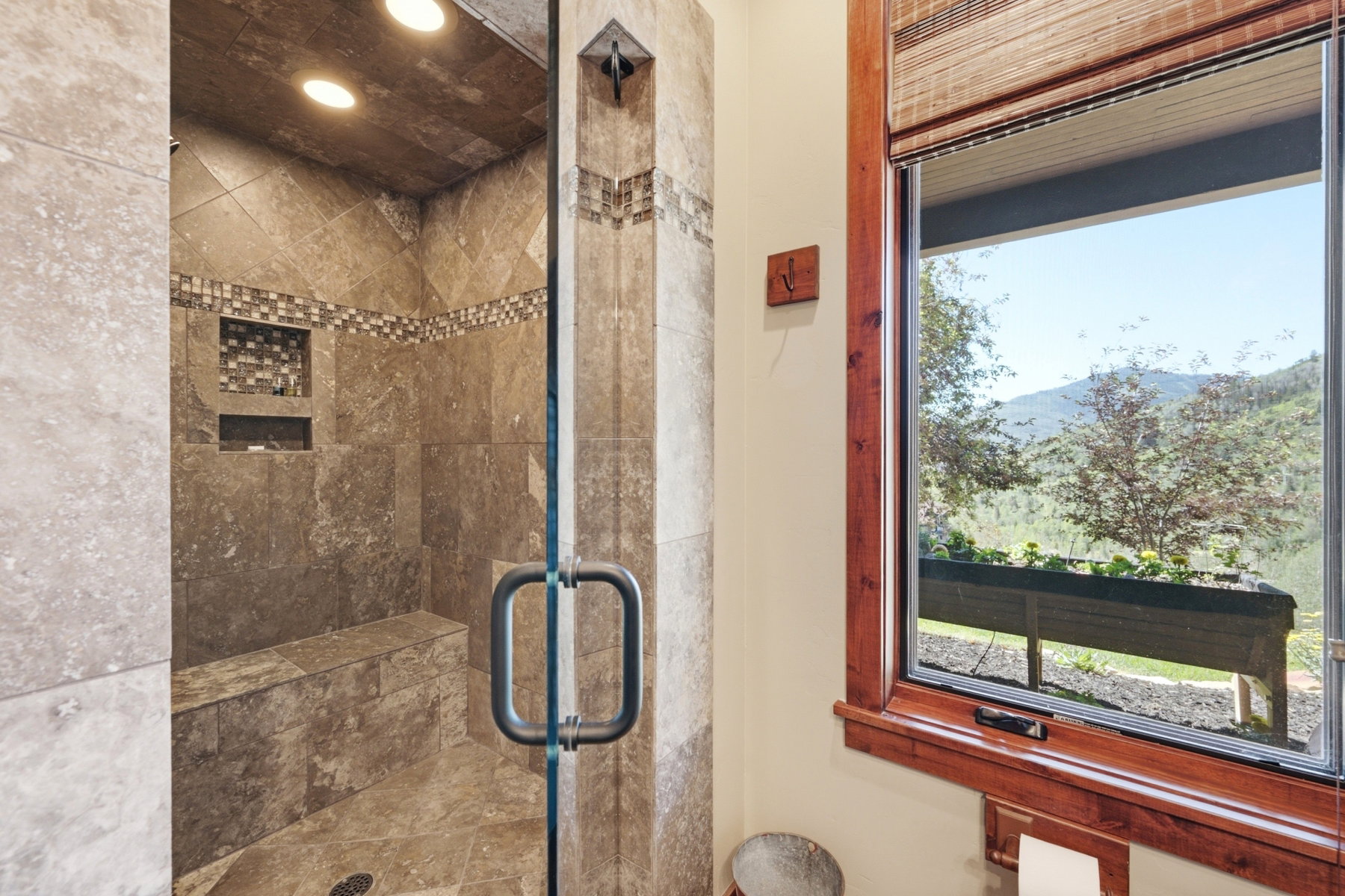 Tiled shower enclosure featuring a built-in bench, recessed lighting, and mosaic tile accents