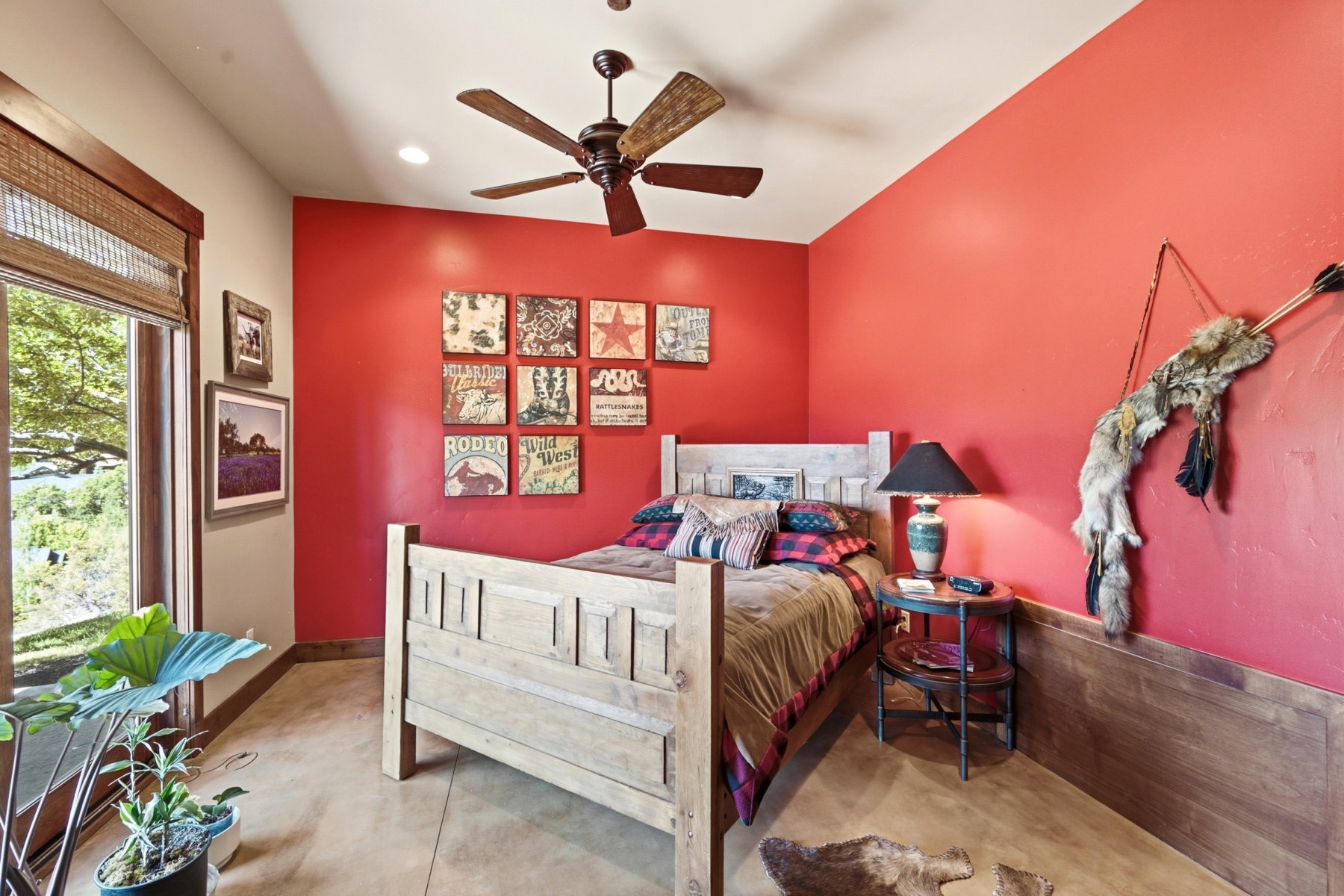 Room featuring an accent wall, wood-finish flooring, a ceiling fan, a window with exterior scenery, and wood trim