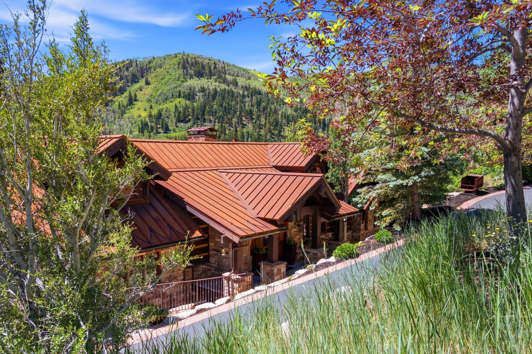 Mountain-style residence featuring a distinctive copper-toned metal roof, stone facade, and exposed timber accents