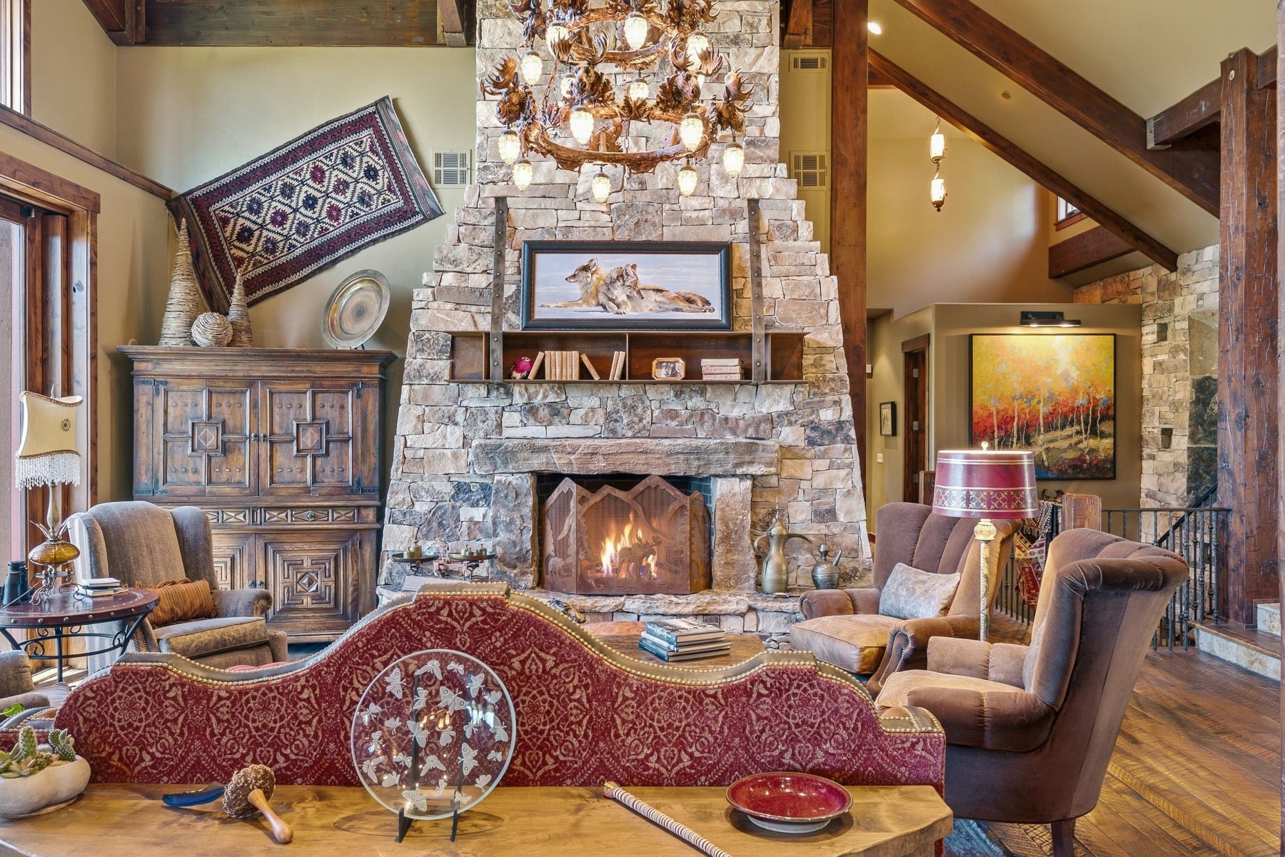 Stone fireplace with a large hearth and mantle, flanked by wood-beamed ceilings and exposed structural wood columns