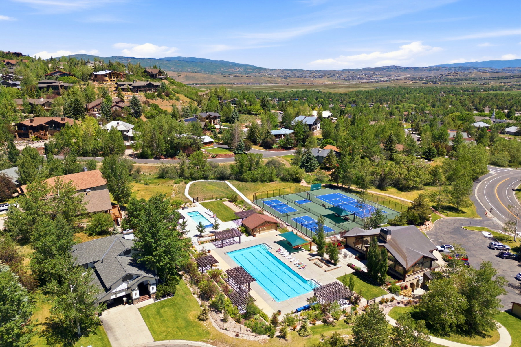 Expansive community amenities featuring a large outdoor swimming pool, multiple tennis courts, and a dedicated clubhouse building