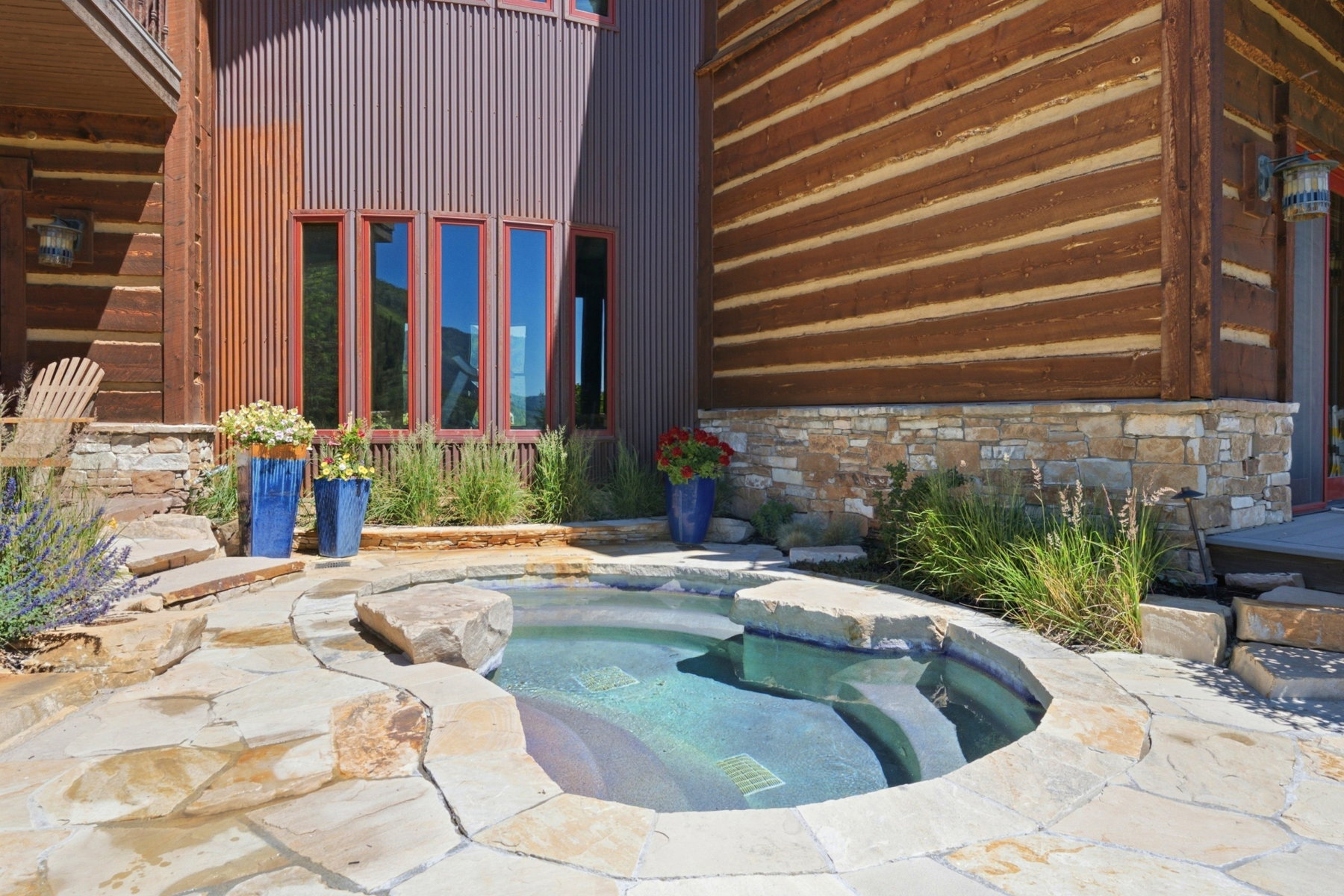 Outdoor spa with natural stone coping and integrated stone steps, surrounded by flagstone patio