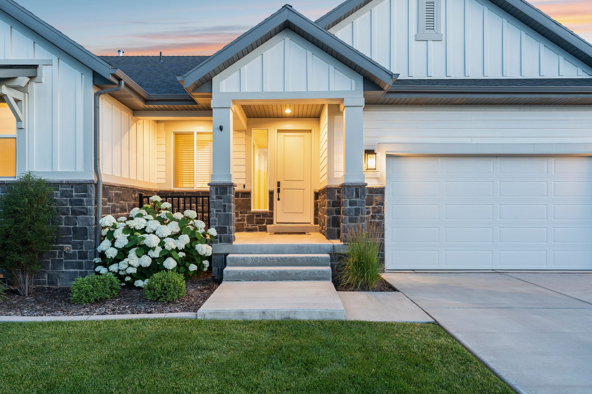 Modern farmhouse exterior featuring white siding, stone veneer accents, and a covered entry