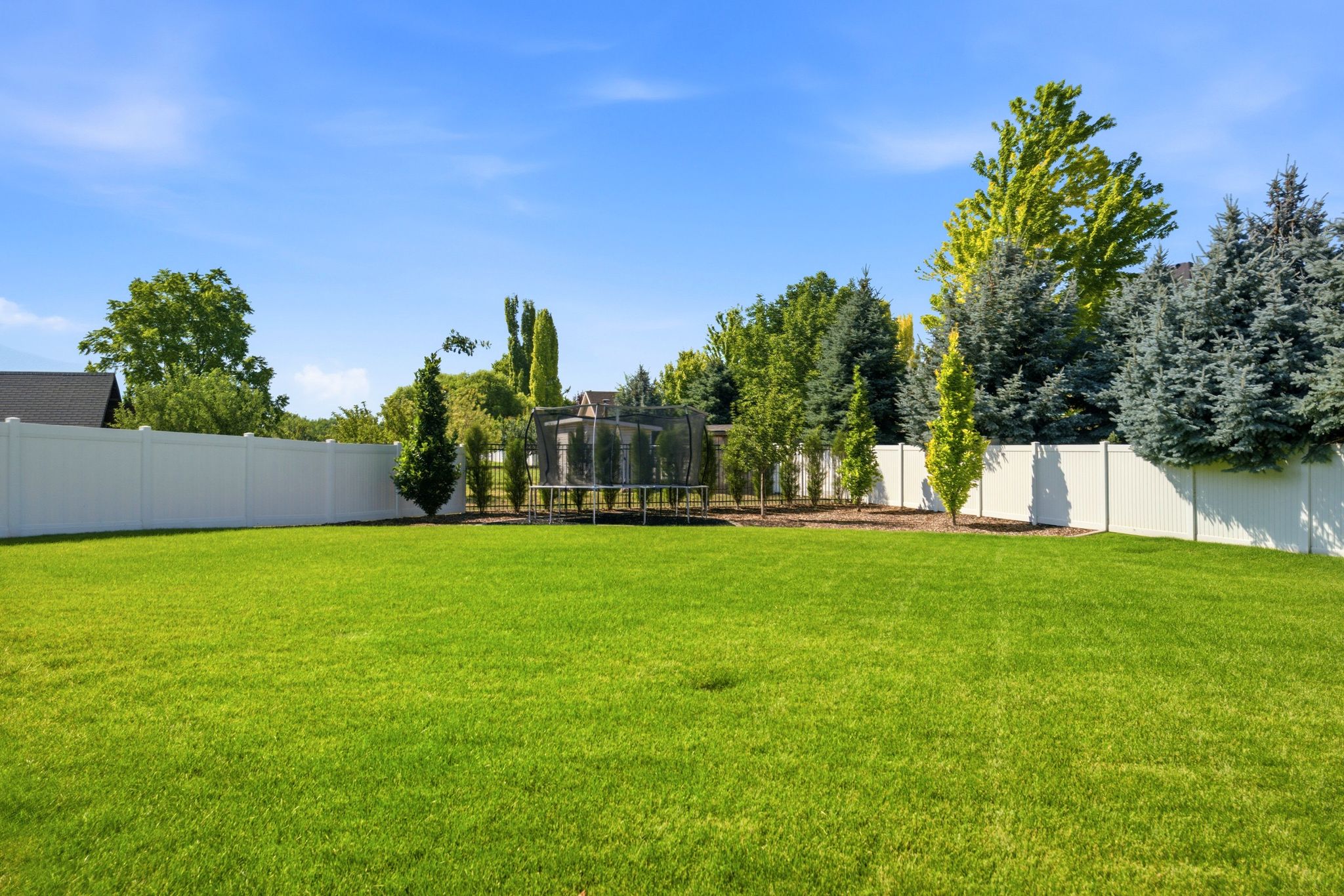 Expansive lawn area featuring a full vinyl privacy fence
