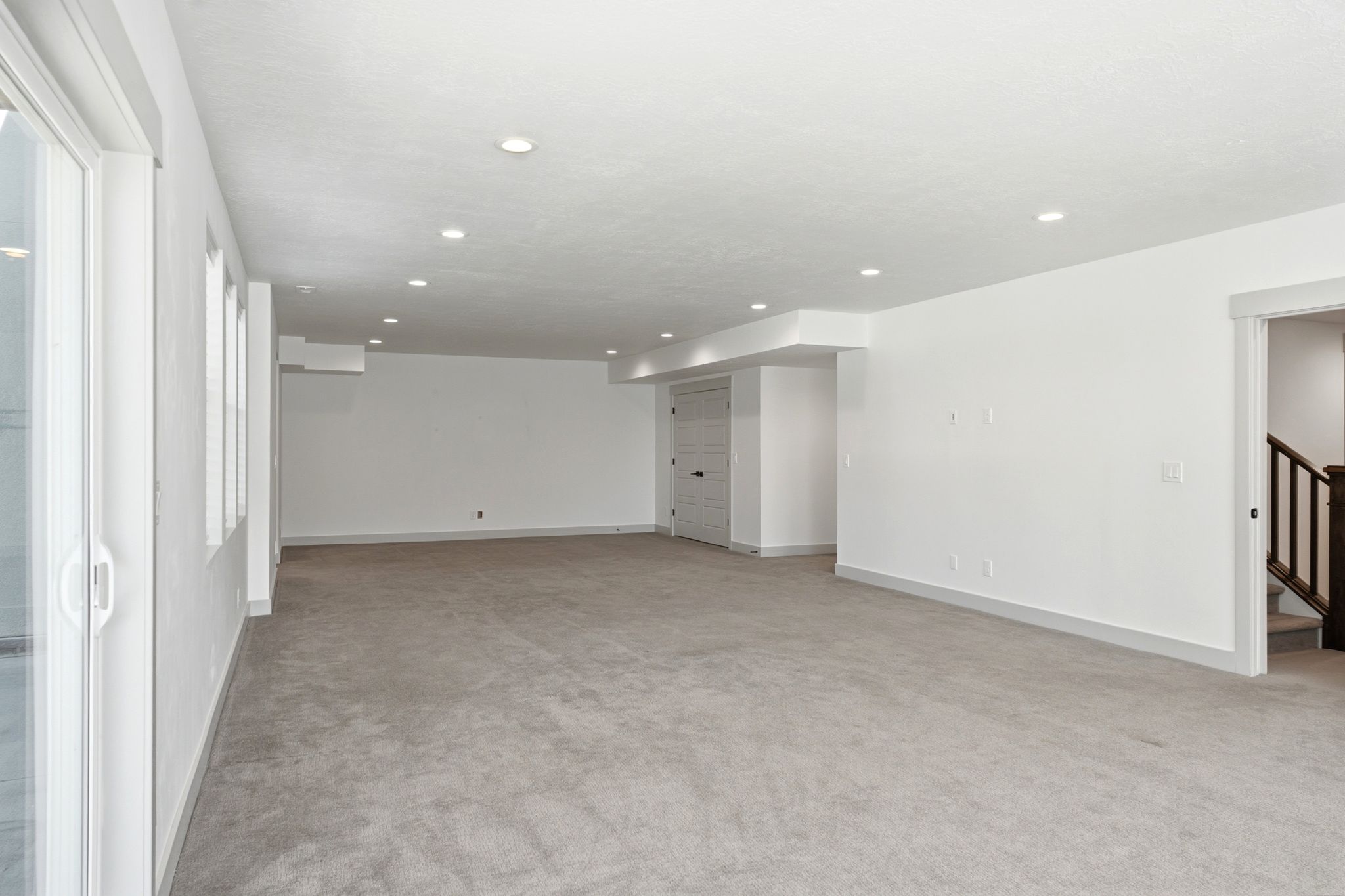 Spacious room featuring light gray carpeting and white walls