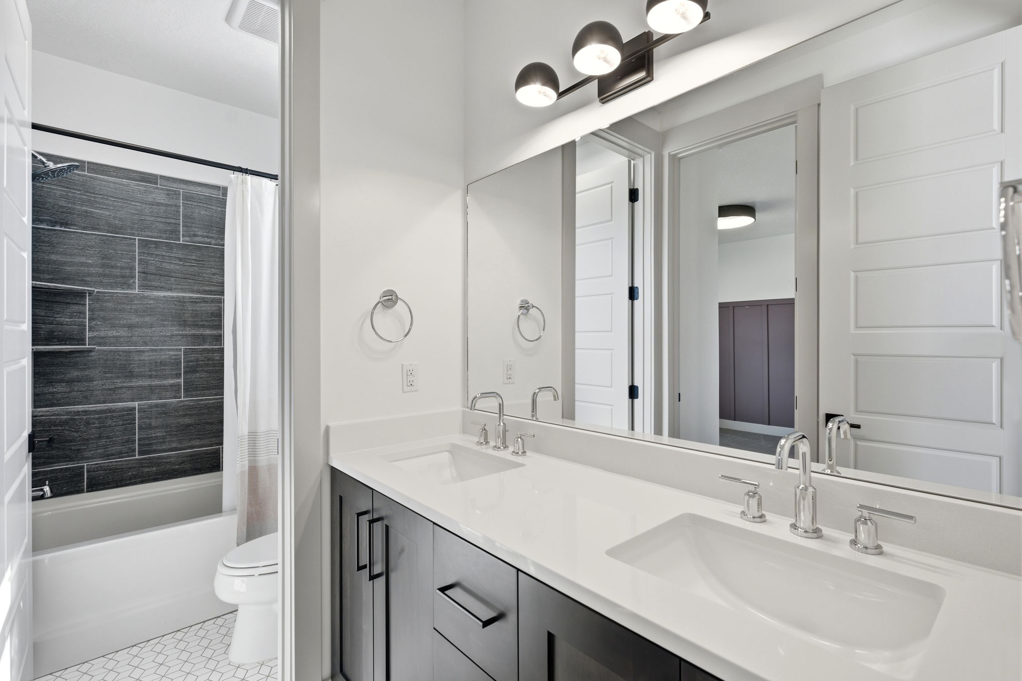 Bathroom featuring a double vanity with white countertops, dark wood-finish cabinetry, and chrome fixtures