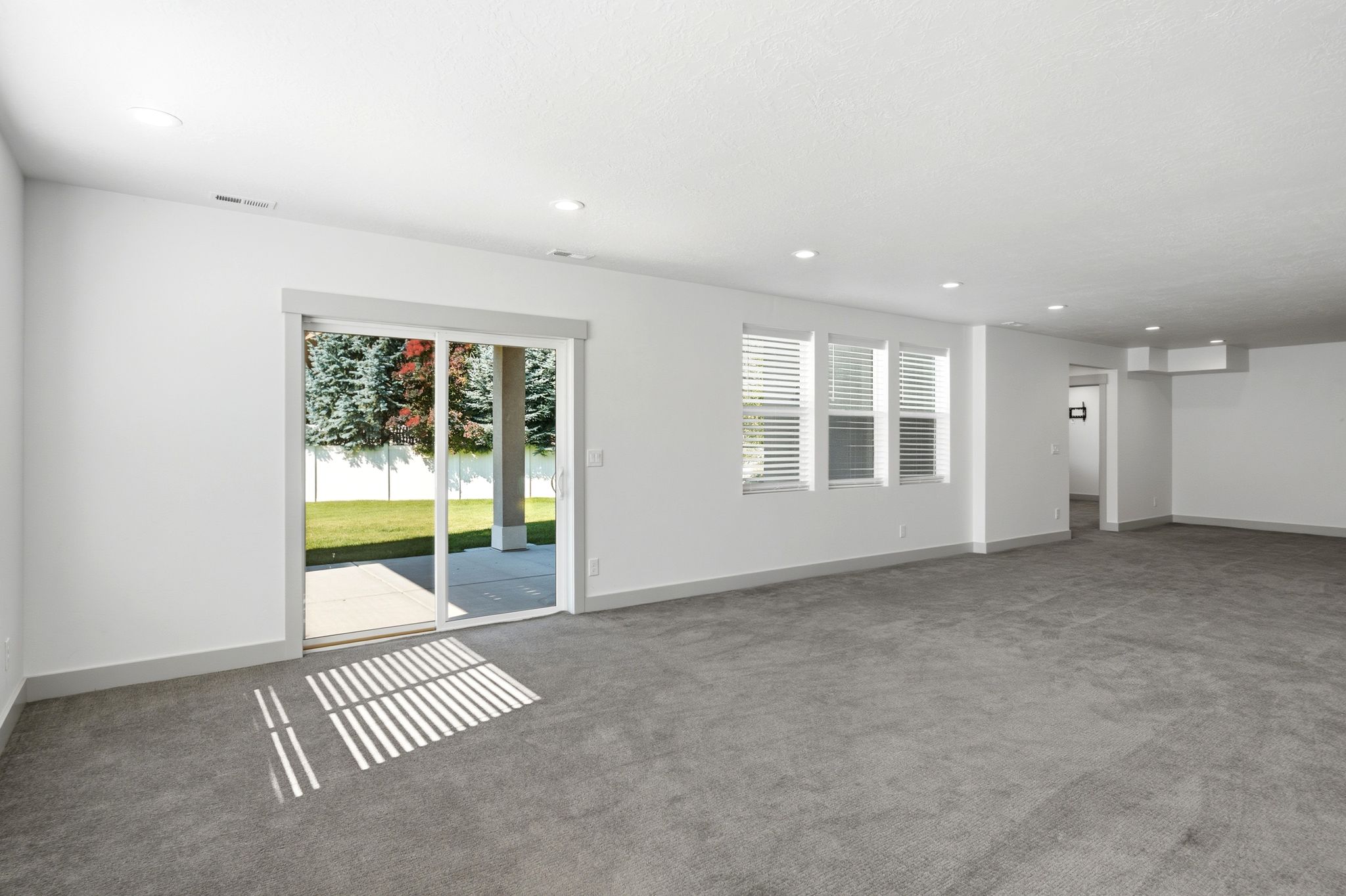 Spacious interior featuring grey carpeting and white walls with contrasting grey baseboards