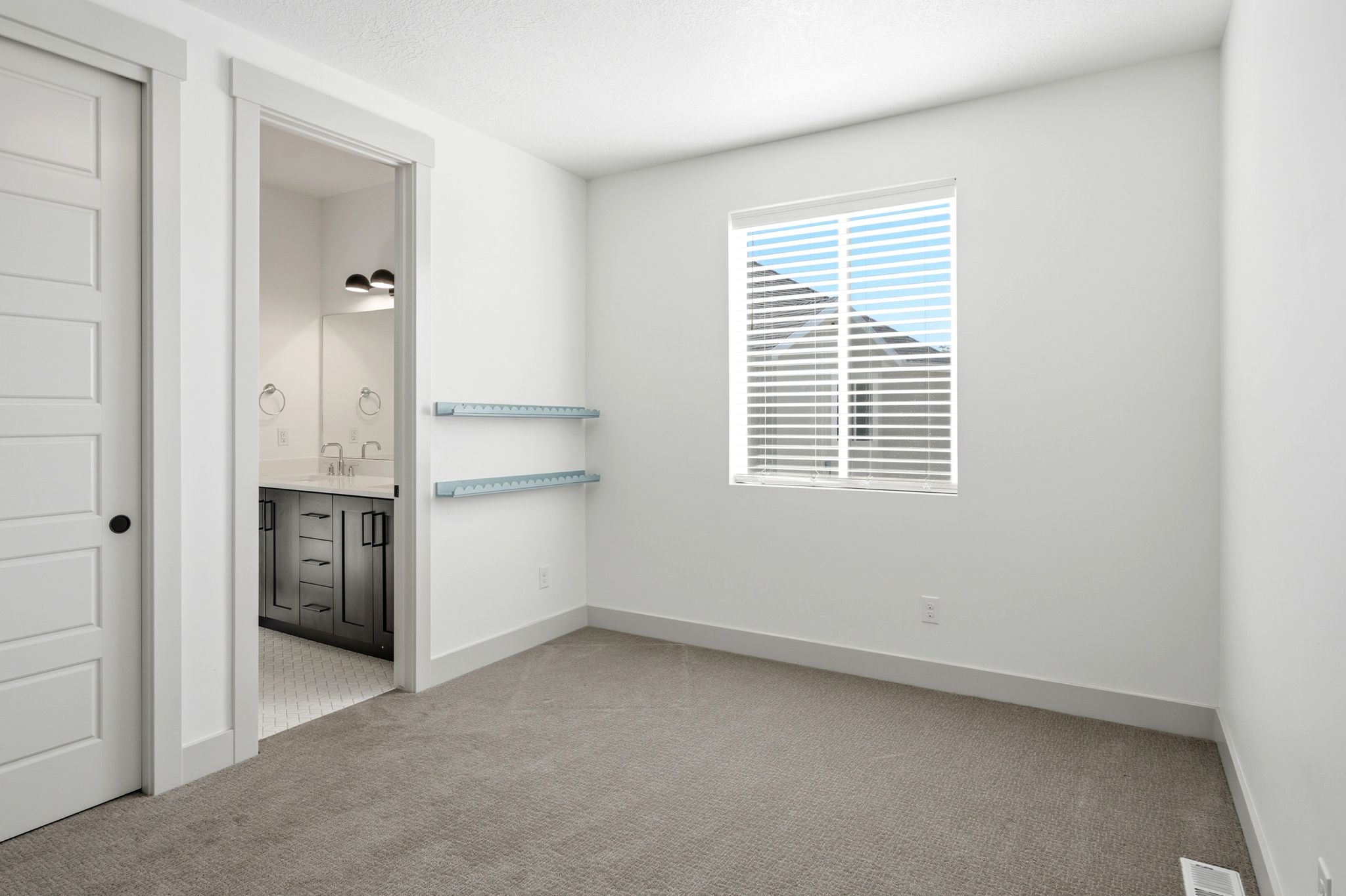 Carpeted room with white walls, a white five-panel interior door with a black knob, and a window with horizontal blinds