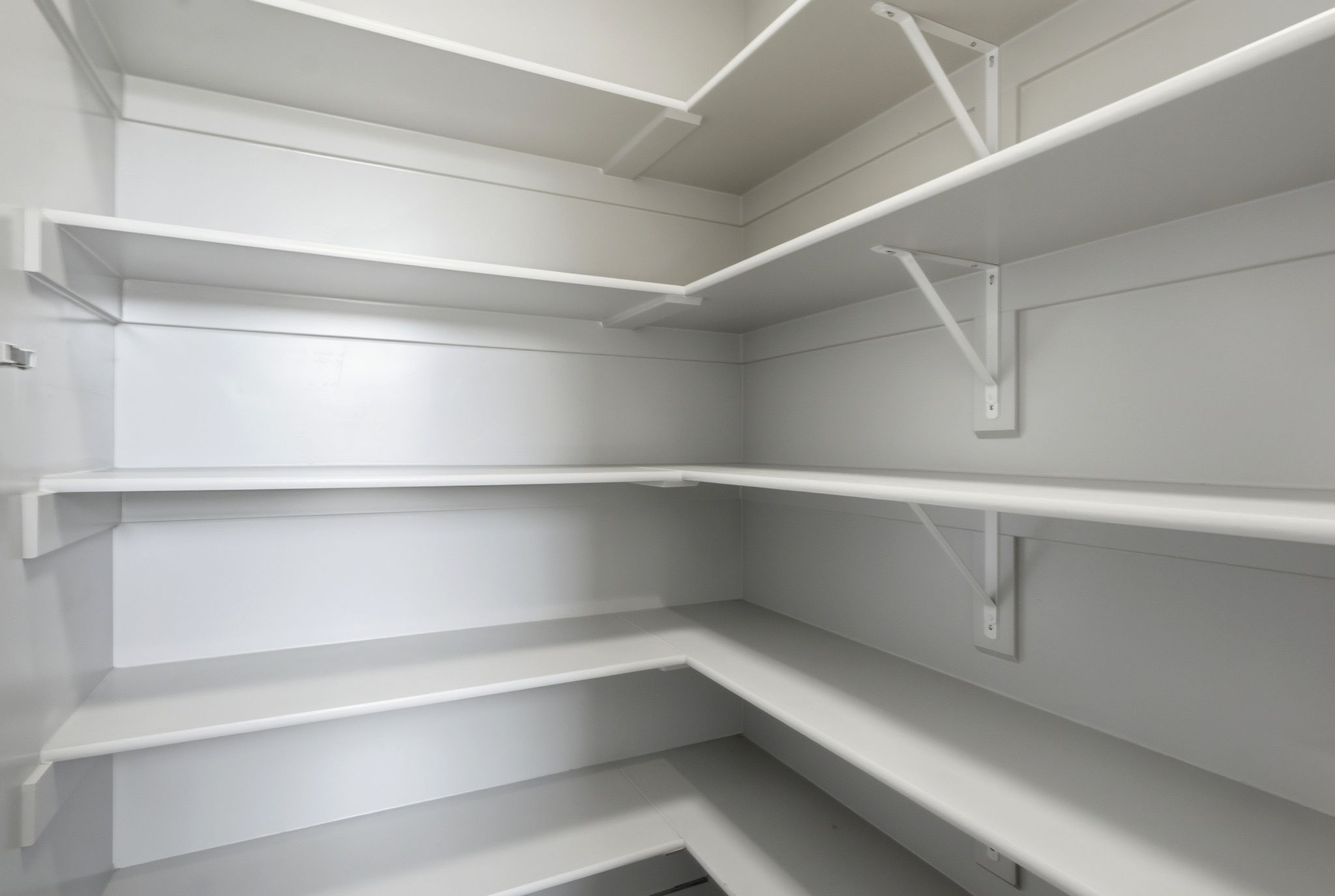 Expansive walk-in pantry featuring multiple levels of white shelving and sturdy support brackets