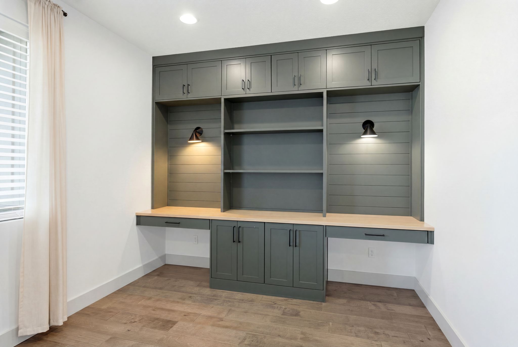 Built-in desk and shelving unit featuring a dark green finish and light wood-finish countertops