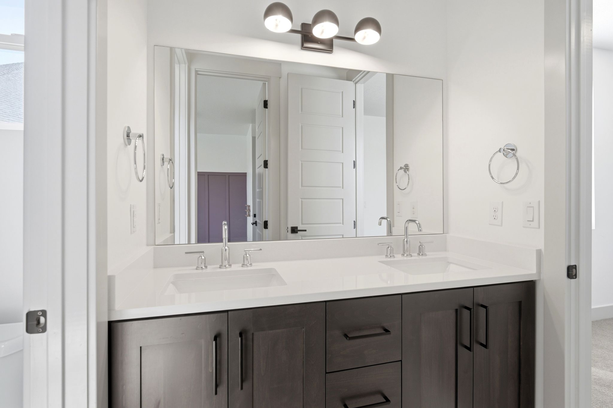 Dual sink vanity with dark wood-finish cabinetry and light-toned countertops