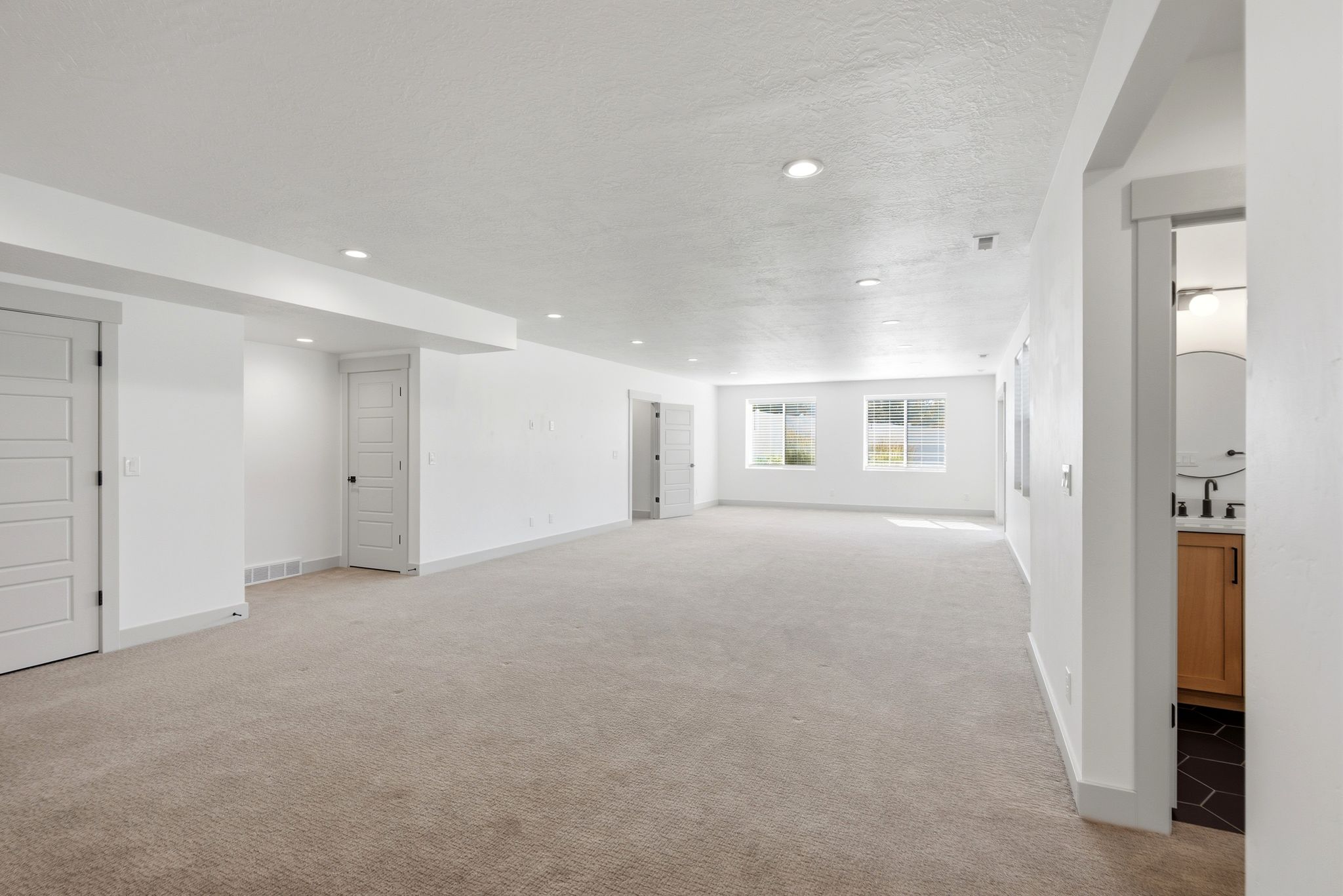 Spacious lower-level area featuring recessed lighting, light-toned carpeting, and multiple windows