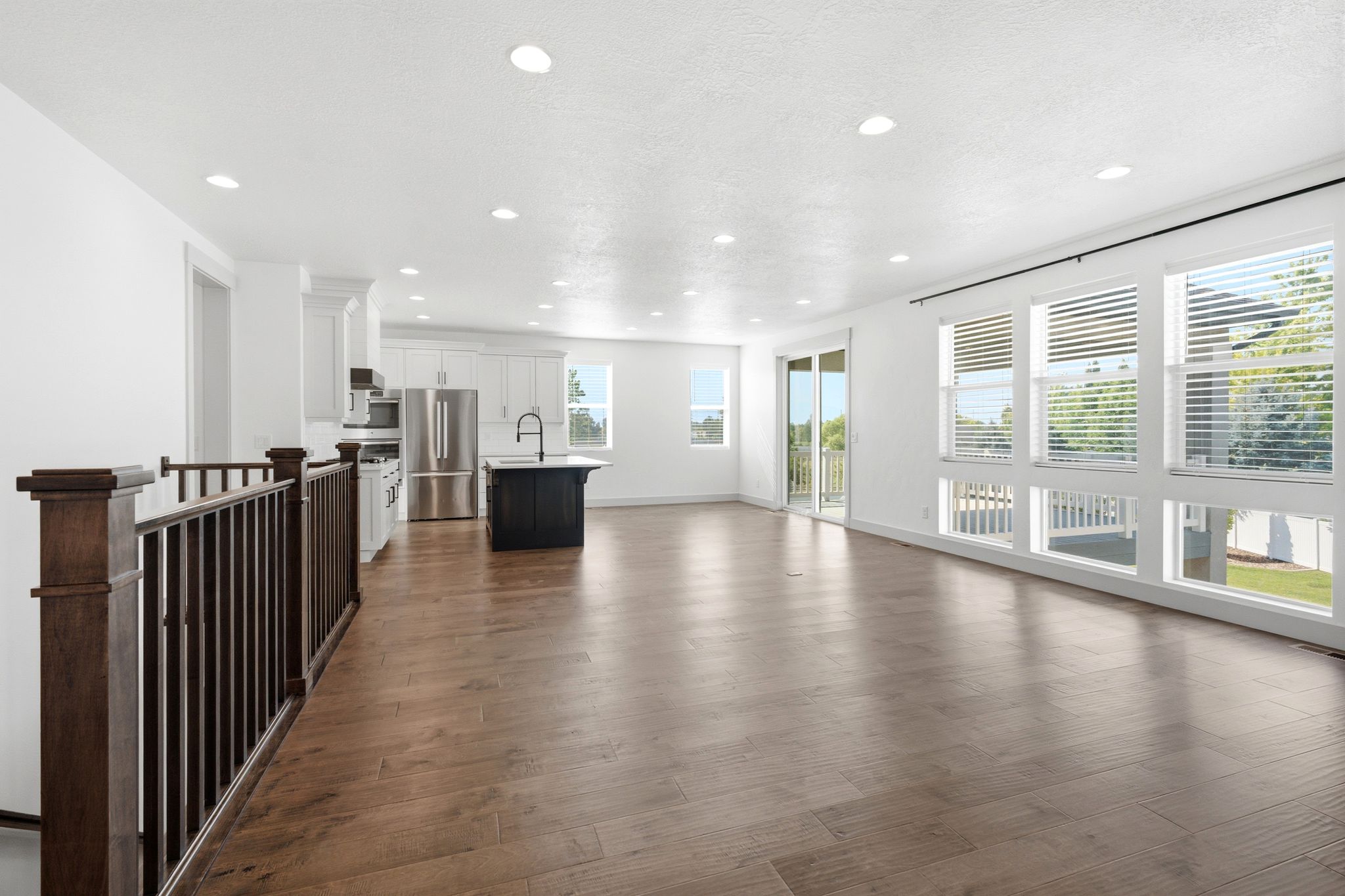 Open-concept living space featuring wood-finish flooring, recessed lighting, and a modern kitchen with a dark-toned island