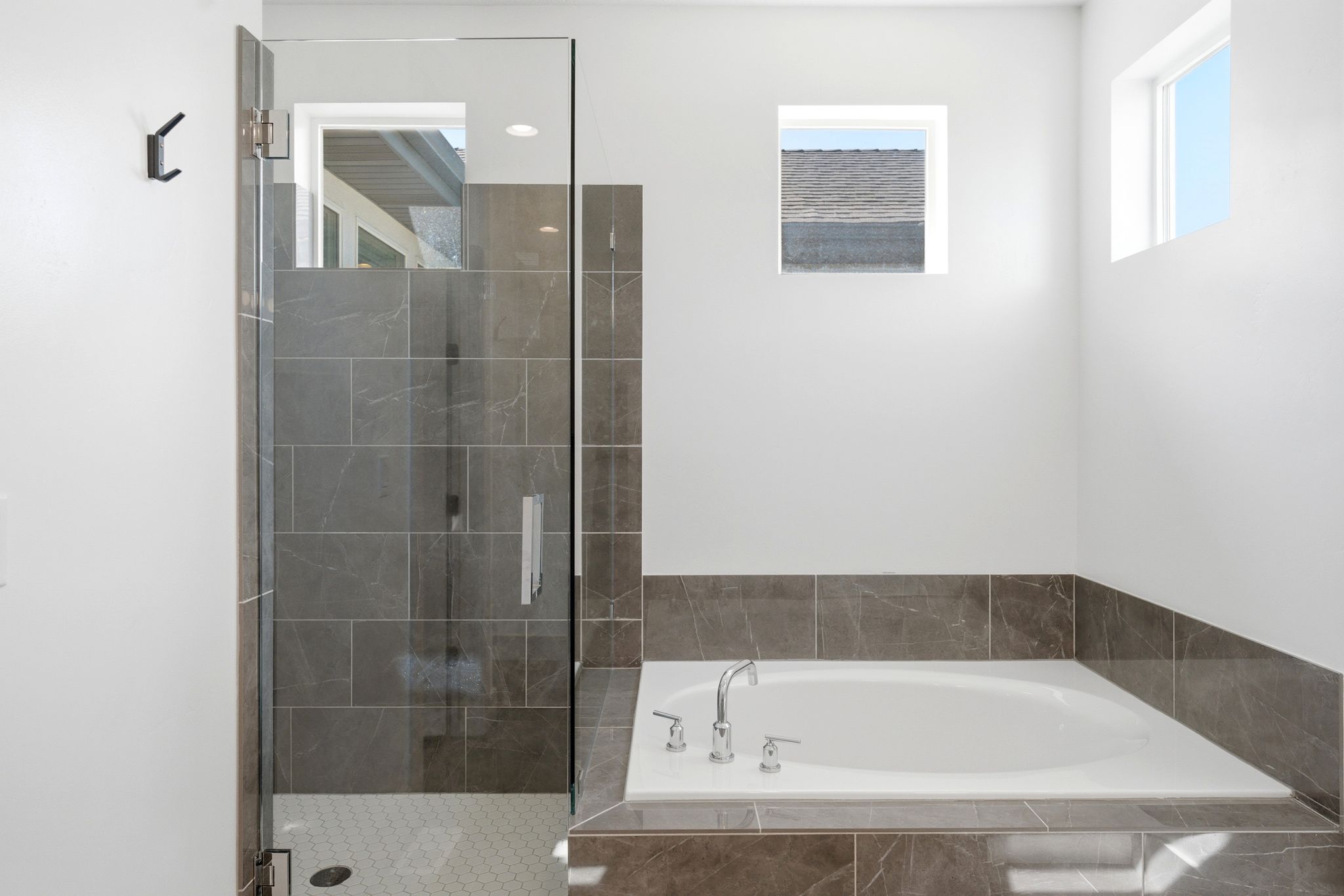 Contemporary bathroom featuring a walk-in shower with clear glass enclosure, tiled surround, and hexagonal floor