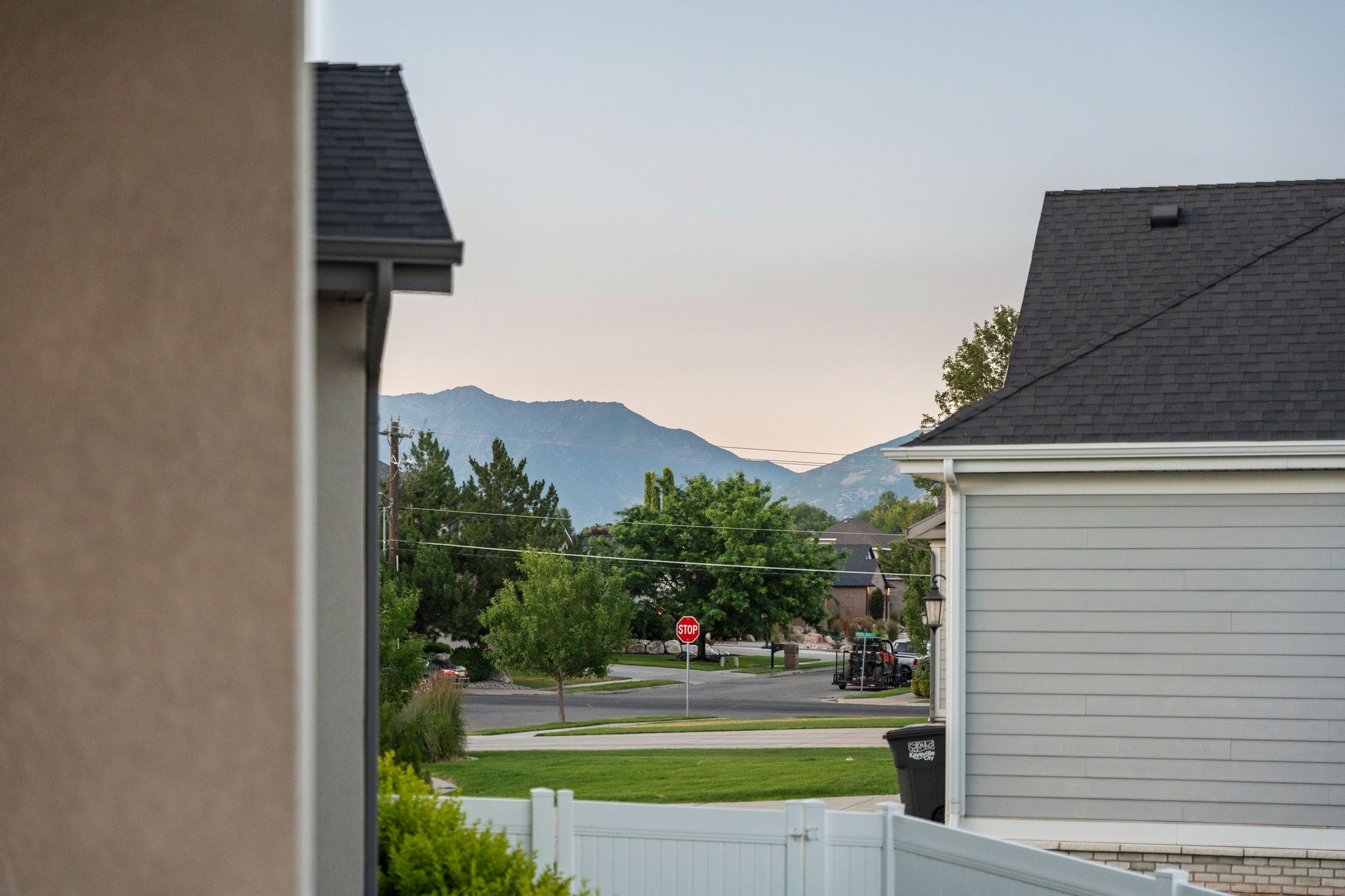Distant mountain range backdrop with mature trees, green lawns, and a white fence