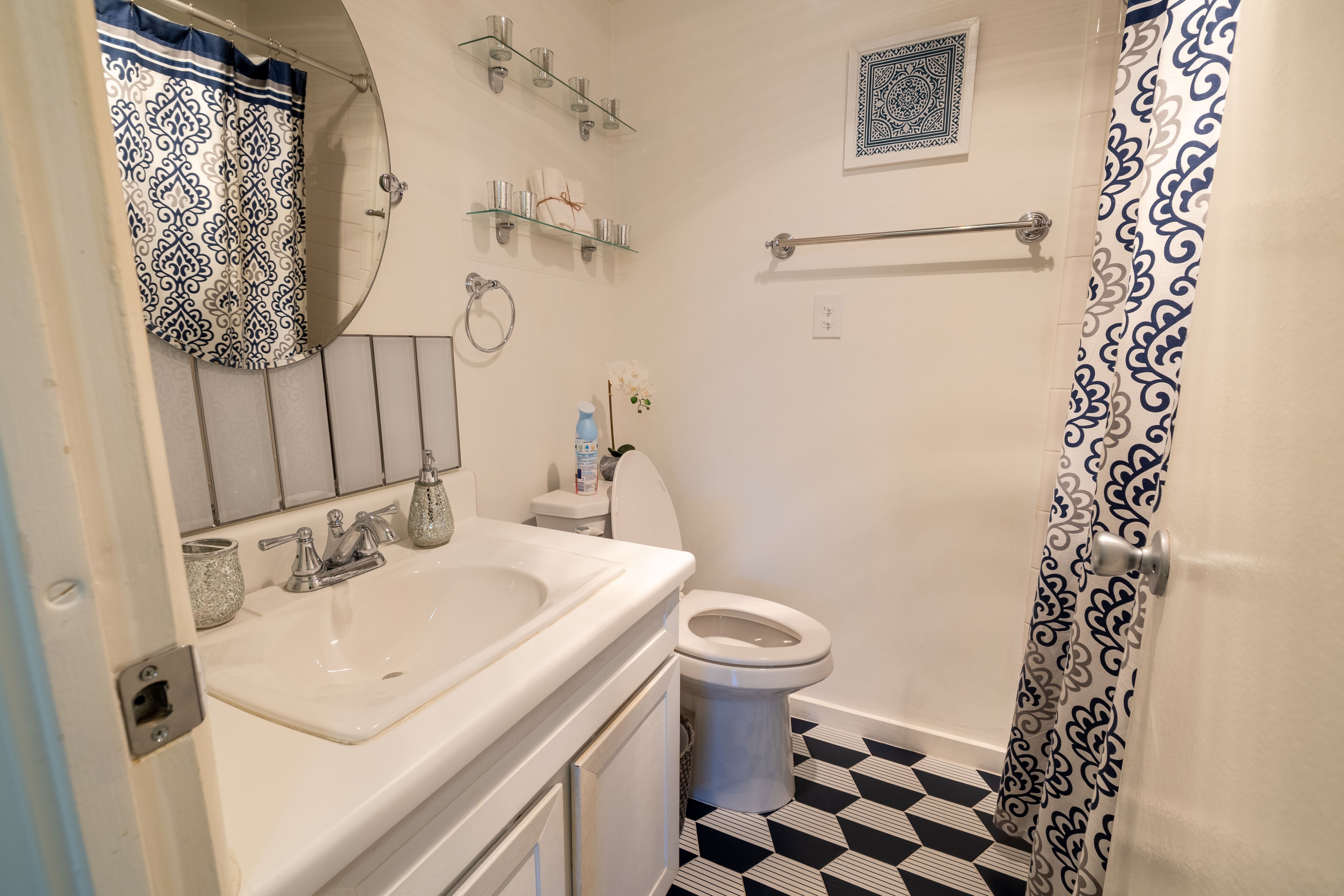 Bathroom featuring a vanity with an integrated sink, polished chrome faucet, and a round mirror