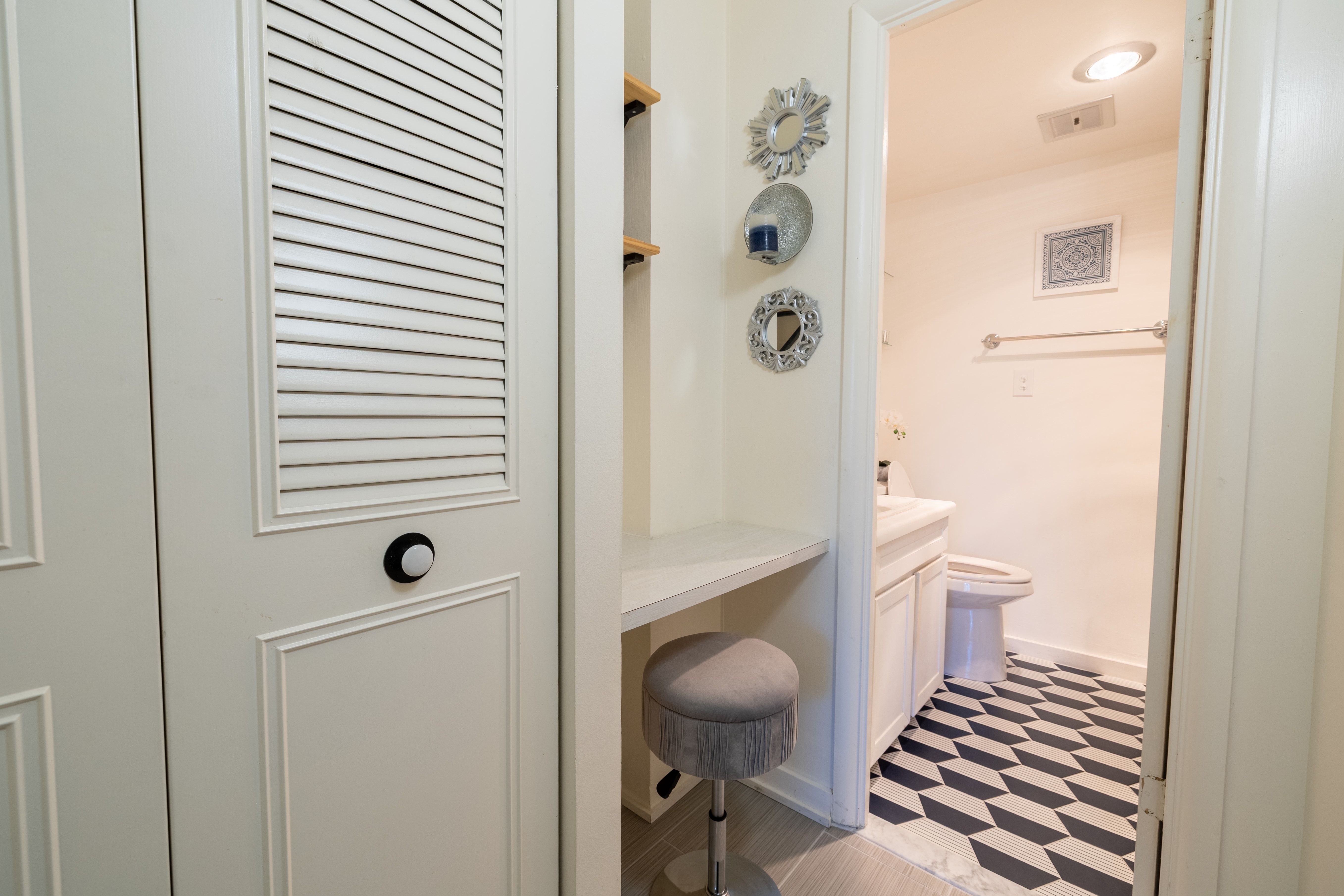 Bathroom with geometric tile flooring, a white vanity with a rectangular sink, and a toilet