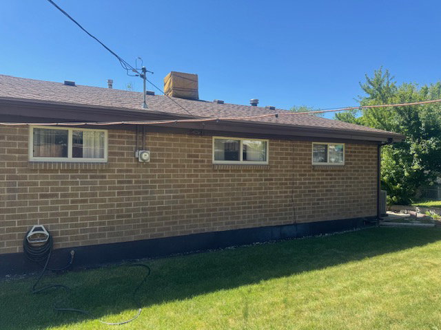 Brick exterior featuring a brown shingle roof, dark brown trim, and multiple windows